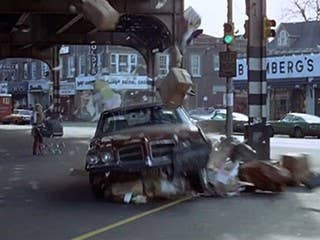 Popeye Doyle, played by Gene Hackman, drives a pretty crappy looking brown 1971 Pontiac LeMans that he steals from a driver he stops in Queens as he is pursuing his quarry. The bad guy gets on an elevated train and he thinks he loses Popeye. But Doyle pursues the train under the tracks on the streets below in his borrowed LeMans.  What is remarkable is that Hackman did his own driving in this legendary chase scene. And in one of the takes, he actually hits a civilian car, driven buy a guy who managed to get through the barricades set up by the production crew to protect the early morning shoot.  The LeMans does excellent duty, being driven at times around 80 mph under the trains trestles, and enduring several bashes and collisions along the way before Popeye catches up with the guy and shoots him on he steps as he is descending to what he thinks is safety. Doyle is exhausted but manages to get off a kill-shot with his Smith& Wesson 38.