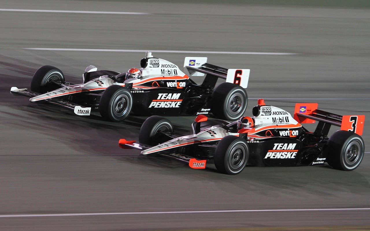 Helio Castroneves (30) runs side-by-side with teammate Ryan Briscoe (6) on his way to winning the IndyCar Series Kentucky Indy 300 auto race at the Kentucky Speedway in Sparta, Ky., Saturday, Sept. 4, 2010.  (AP Photo/James Crisp)