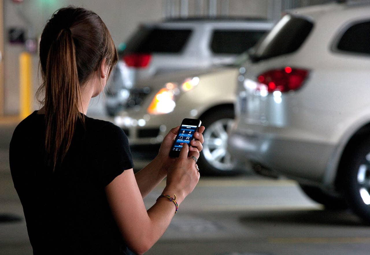 A driver uses the OnStar mobile app technology to sound her vehicles horn and lights to locate her Cadillac SRX in a crowded parking structure. X10CO_ON015 (07/22/2010)