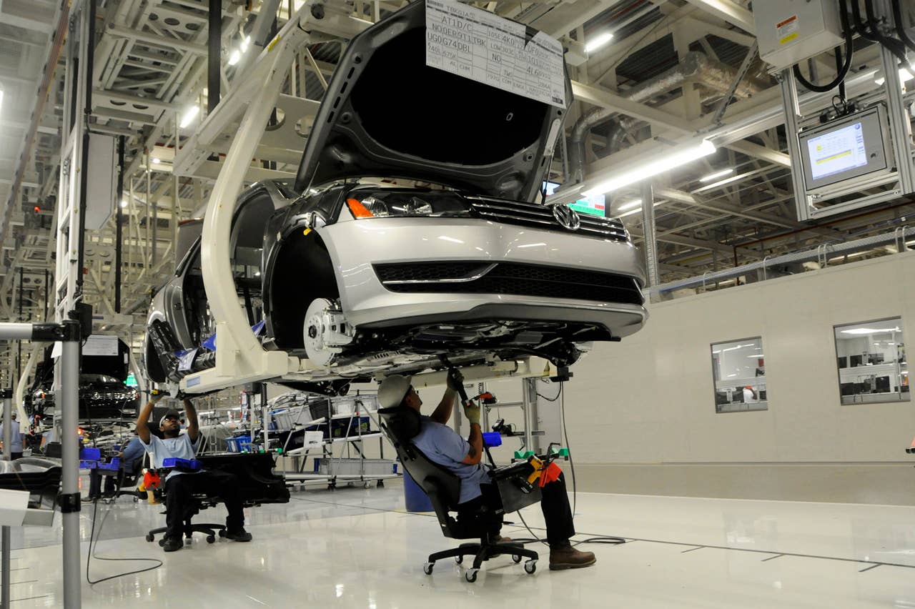 Workers inspect the undercarriage of a new Passat inside the new Volkswagen plant in Chattanooga, Tenn. on Tuesday, May 24, 2011. Volkswagen is jumping into the U.S. auto market with a new Passat that is bigger, cheaper and built domestically in hopes of breaking into the competitive midsize sedan market. (AP Photo/Billy Weeks)