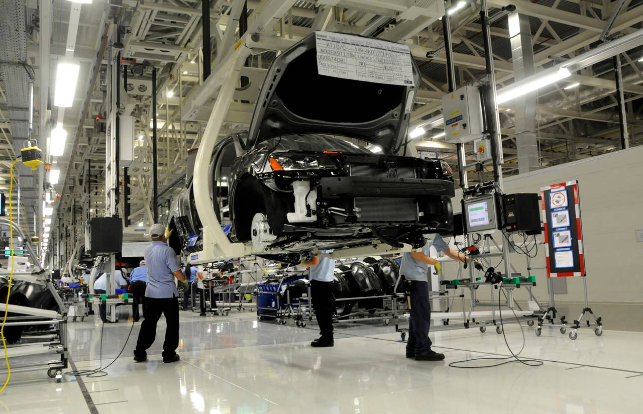 Workers inspect the undercarriage of a new Passat inside the new Volkswagen plant in Chattanooga, Tenn. on Tuesday, May 24, 2011. Volkswagen is jumping into the U.S. auto market with a new Passat that is bigger, cheaper and built domestically in hopes of breaking into the competitive midsize sedan market. (AP Photo/Billy Weeks)
