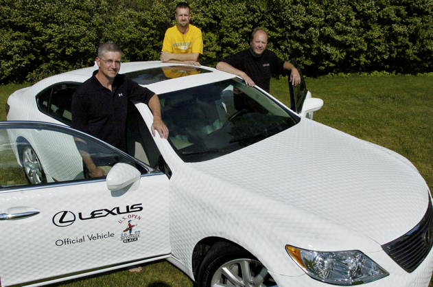 Brad Smith and Rick and Matt Davis, in back, stand with a Lexus LS 460L Tuesday afternoon that they retrofitted with golf ball style paneling for Lexus to be the Official Vehicle at this weekend's U.S. Open. The trio took 12 weeks to design the dimple panels that were taken from the concept of Smith's golf ball mailbox. GAVIN JACKSON/The Lima News