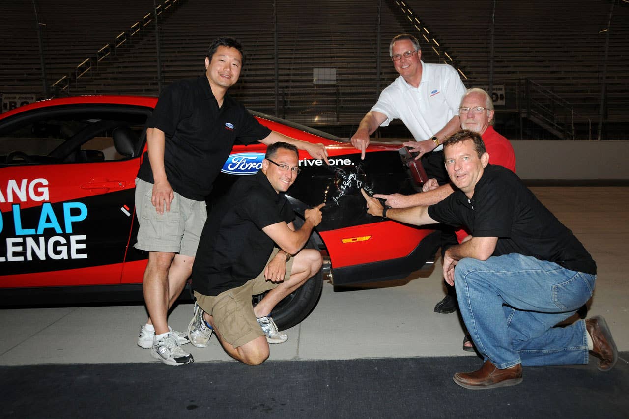 06/23/10 Bristol, Tn. - Pointing to their signatures on the sealed fuel tank, members of the Mustang 1000 Lap Challenge driving team celebrate after the 2011 Mustang V6 ran out of fuel after 1,457 laps at Bristol Motor Speedway.  l-r Seong Park - Mustang engineer, Jonathan Mehl - Mustang engineer, Tim Duerr - Ford Racing, Carl Ek - Mustang engineer and Tom Barnes - Mustang engineer.  2010, Paul Webb