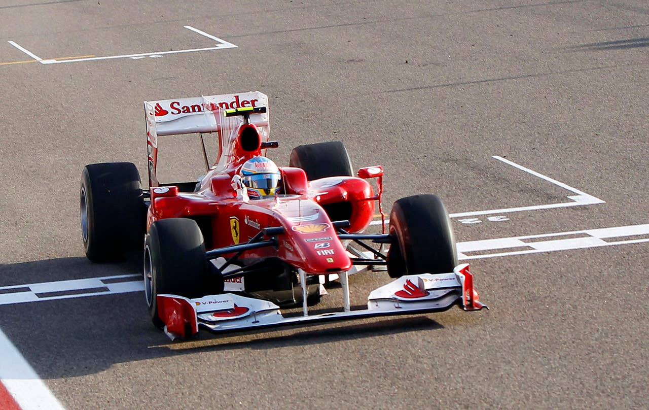 Ferrari's Spanish driver Fernando Alonso celebrates as he crosses the finish line of the Bahrain international circuit on March 14, 2010 in Manama, after the Bahrain Formula One Grand Prix. Ferrari's Spanish driver Fernando Alonso won the race ahead of his Brazilian team mate Felipe Massa and McLaren Mercedes' British driver Lewis Hamilton.                AFP PHOTO / POOL / LUCA BRUNO (Photo credit should read LUCA BRUNO/AFP/Getty Images)