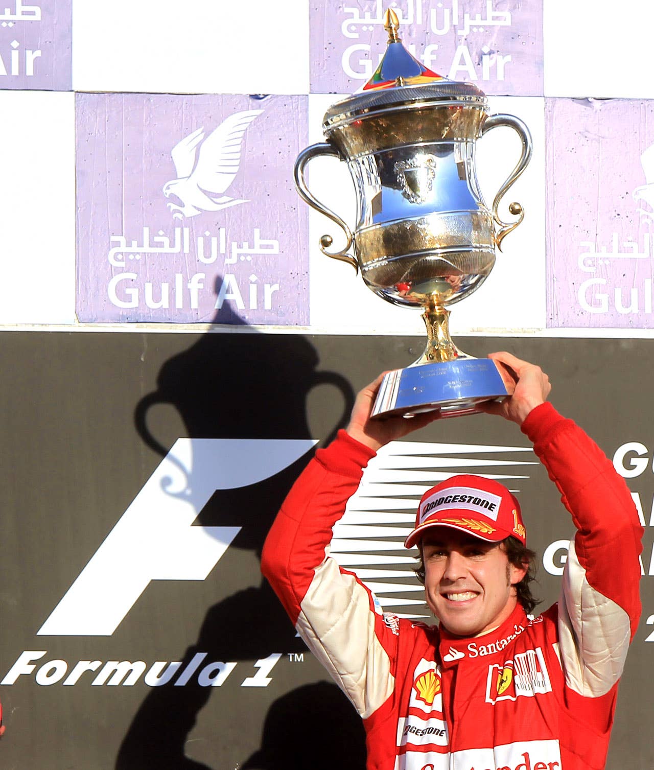 Ferrari's Spanish driver Fernando Alonso celebrates on the podium of the Bahrain international circuit on March 14, 2010 in Manama, after the Bahrain Formula One Grand Prix. Ferrari's Spanish driver Fernando Alonso won the race ahead of his Brazilian team mate Felipe Massa and McLaren Mercedes' British driver Lewis Hamilton.            AFP PHOTO / KHALED DESOUKI (Photo credit should read KHALED DESOUKI/AFP/Getty Images)