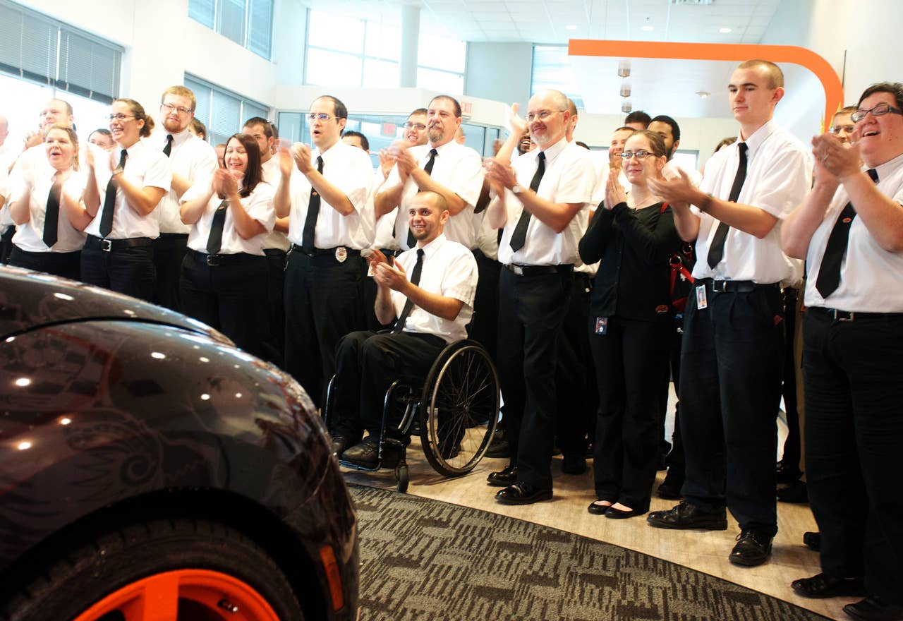 Geek Squad Agents cheer the arrival of  a "tricked-out" Geekmobile from West Coast Customs at Geek Squad City Friday, Dec. 7, 2012 in Louisville, Ky. (Photo by Joe Imel/Invision for Best Buy/AP Images)