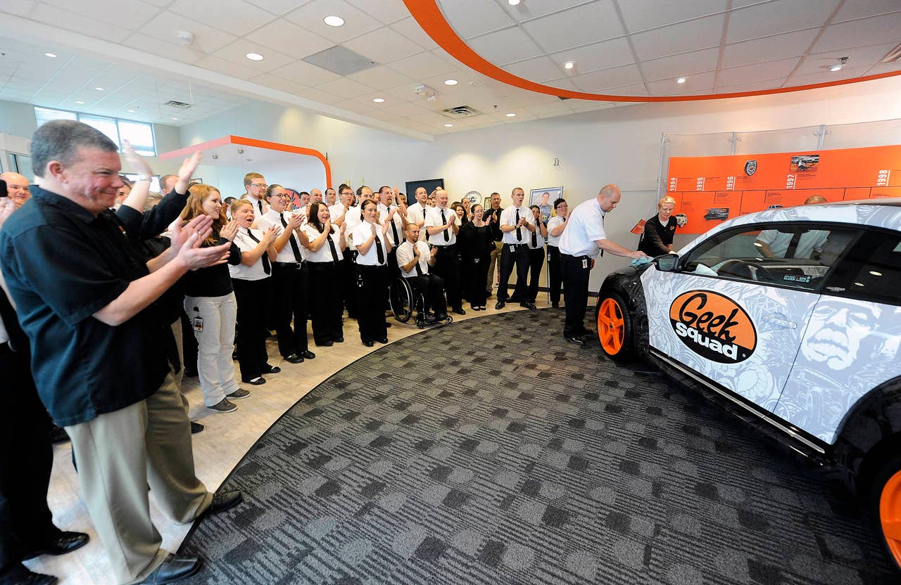 Geek Squad City Mayor Wes Snyder (left) and a crowd of Agents cheer the arrival of a "tricked-out" Geekmobile from West Coast Customs at Geek Squad City Friday, Dec. 7, 2012 in Louisville, Ky. (Photo by Joe Imel/Invision for Best Buy/AP Images)
