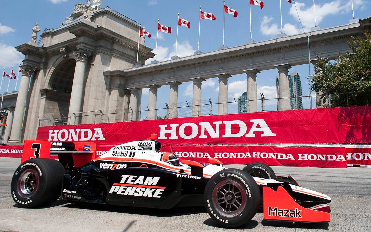 Helio Castroneves, of Brazil, drives in front of Prince's Gate during the second practice session for the IndyCar Series' Honda Indy Toronto auto race in Toronto on Friday, July 16, 2010.