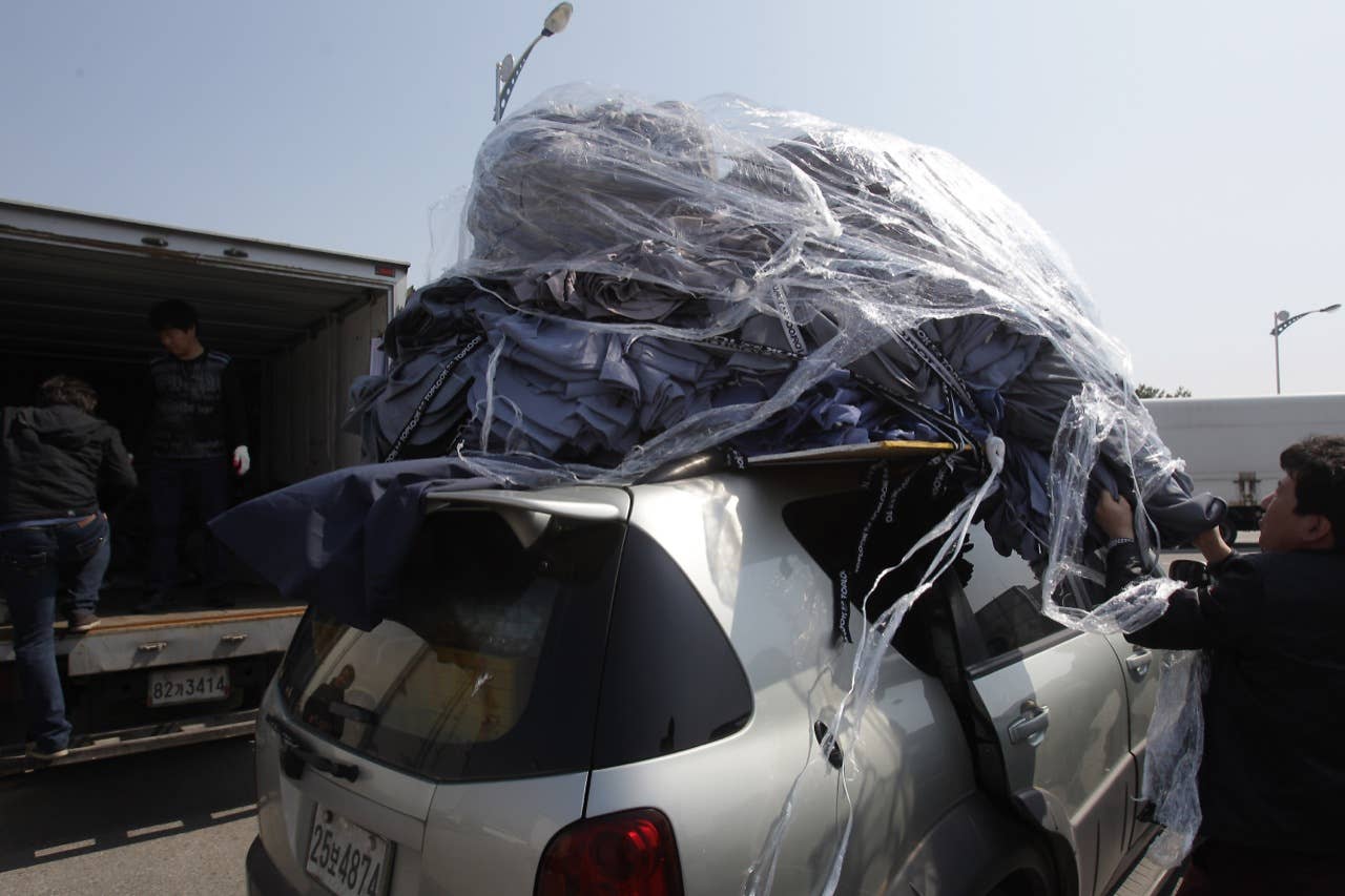 PAJU, SOUTH KOREA - APRIL 27: South Korean workers unload their products made in North Korea's after arrive from the Kaesong joint industrial complex in North Korea at the inter-Korean transit office on April 27, 2013 in Paju, South Korea. South Korean Unification Ministry annouced yesterday to withdraw all 170 remaining workers from Kaesong industrial complex after failing to persuade the North to restart the talk seeking the normalization of Kaesong's operation. (Photo by Chung Sung-Jun/Getty Images)