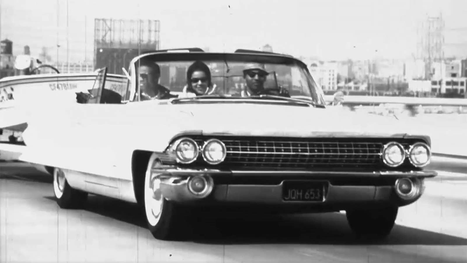 Black people driving a 1962 Cadillac