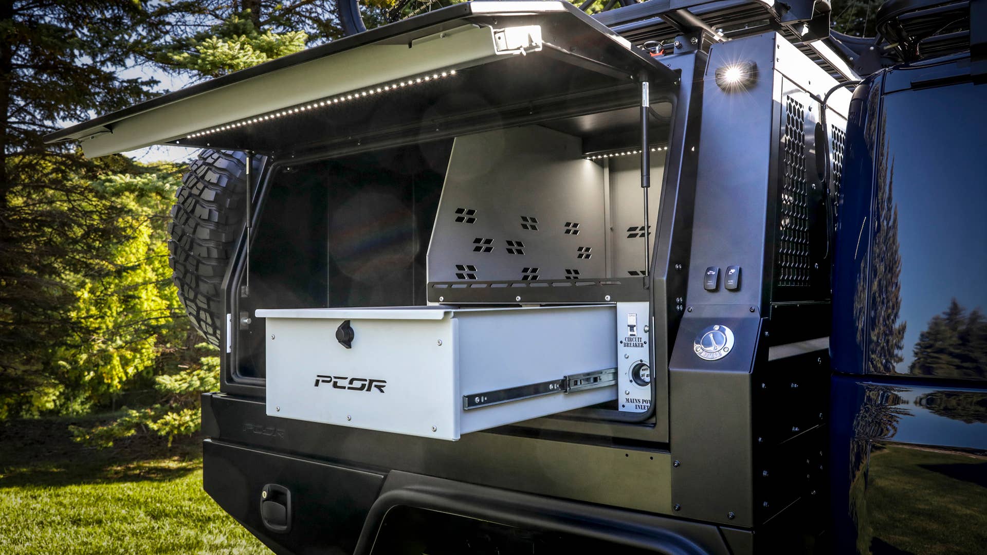 On the passenger-side of the PCOR storage system of the Jeep Gladiator Top Dog Concept, pull-out drawers securely store tools and supplies that mountain bikers need when out on the trails. Vast interior storage shelves, exterior lighting switches and extra power supplies are within easy reach.
