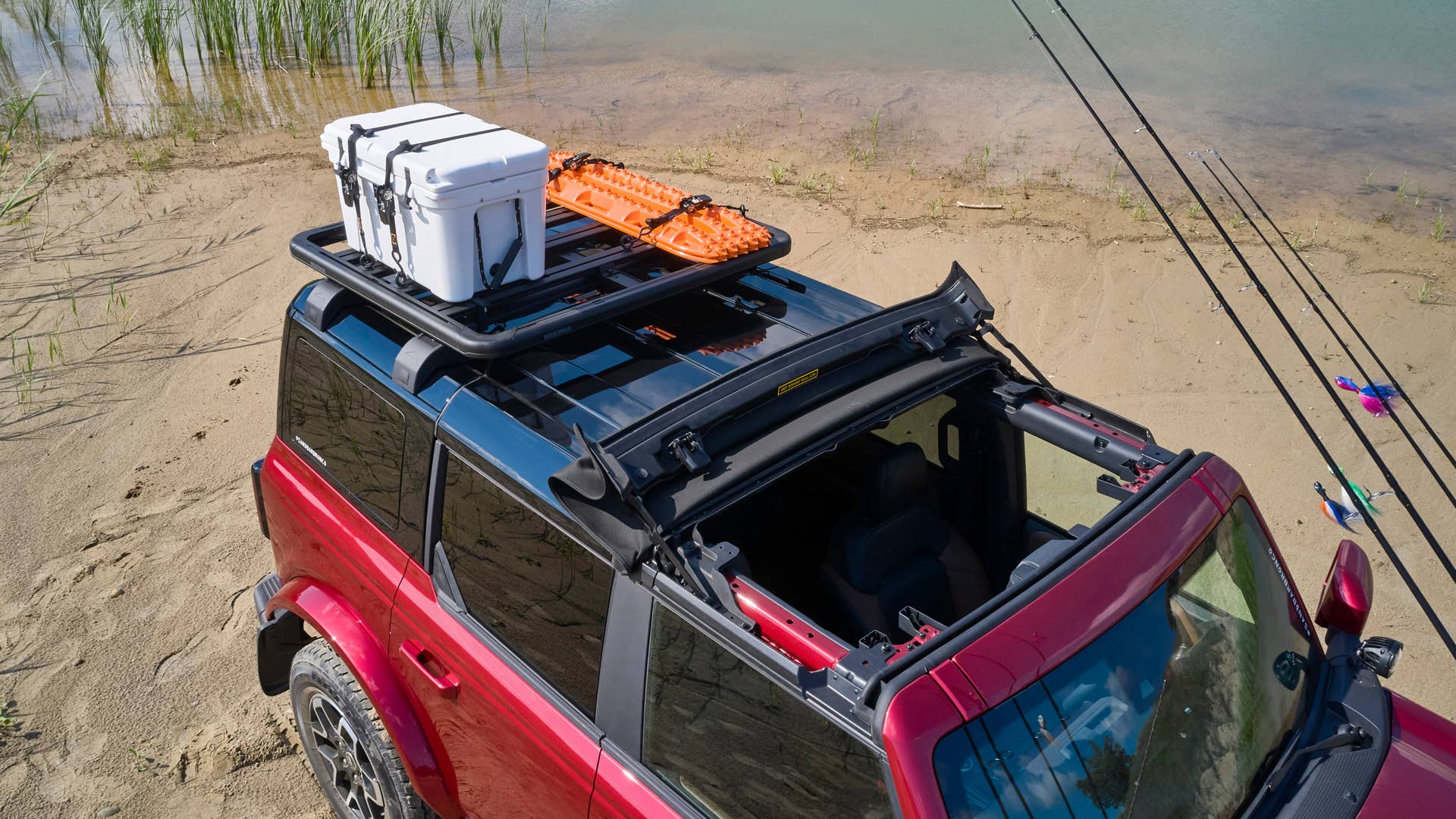 Bronco Four-Door Outer Banks Fishing Guide. Purpose-built to support a professional fishing guide along Cape Hatteras National Seashore, this lifestyle concept is based off the regionally inspired four-door Bronco Outer Banks™ series. On top is a Bestop® Sunrider® first-row soft top, factory-style concept roof rails and crossbars, and a Yakima® LockNLoad™ Platform roof rack. The SUV makes use of fender-mounted trail sights to fit a custom-made fishing pole and seat perch to wait for the perfect catch. A Ford Performance modular front bumper and safari bar help push through rugged terrain, while a slide-out tailgate* provides a great work surface when repairing fishing rods or stringing up new lures. All-weather floor mats and splash guards round out the package. (Preproduction image with optional features shown. Available beginning Spring 2021.) (*Available late 2021)
