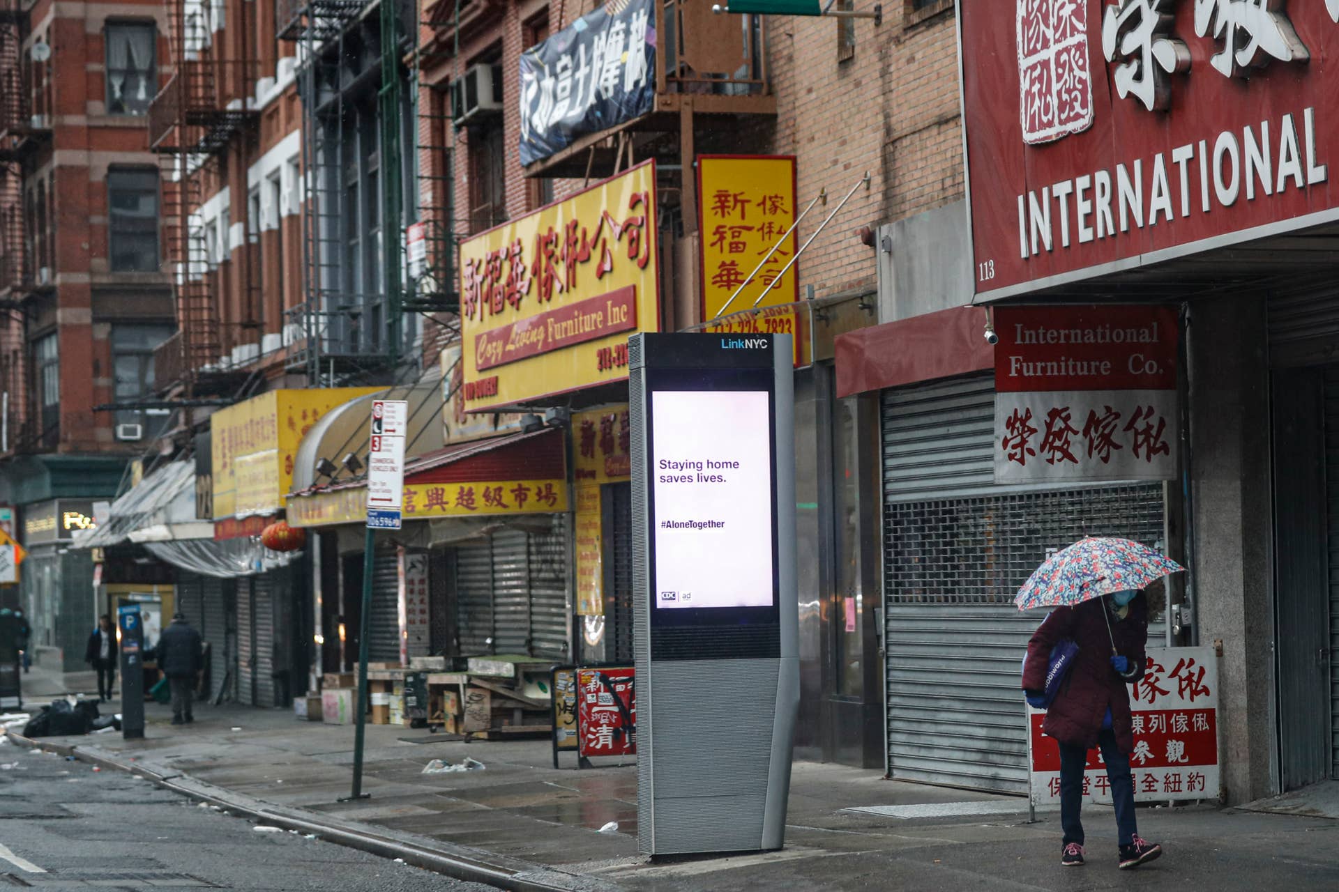 A lone pedestrian walks down the Bowery while wearing a protective mask and glass as a sign urging people to remain home due to coronavirus concerns is displayed, Monday, March 23, 2020, in New York. (AP Photo/John Minchillo)