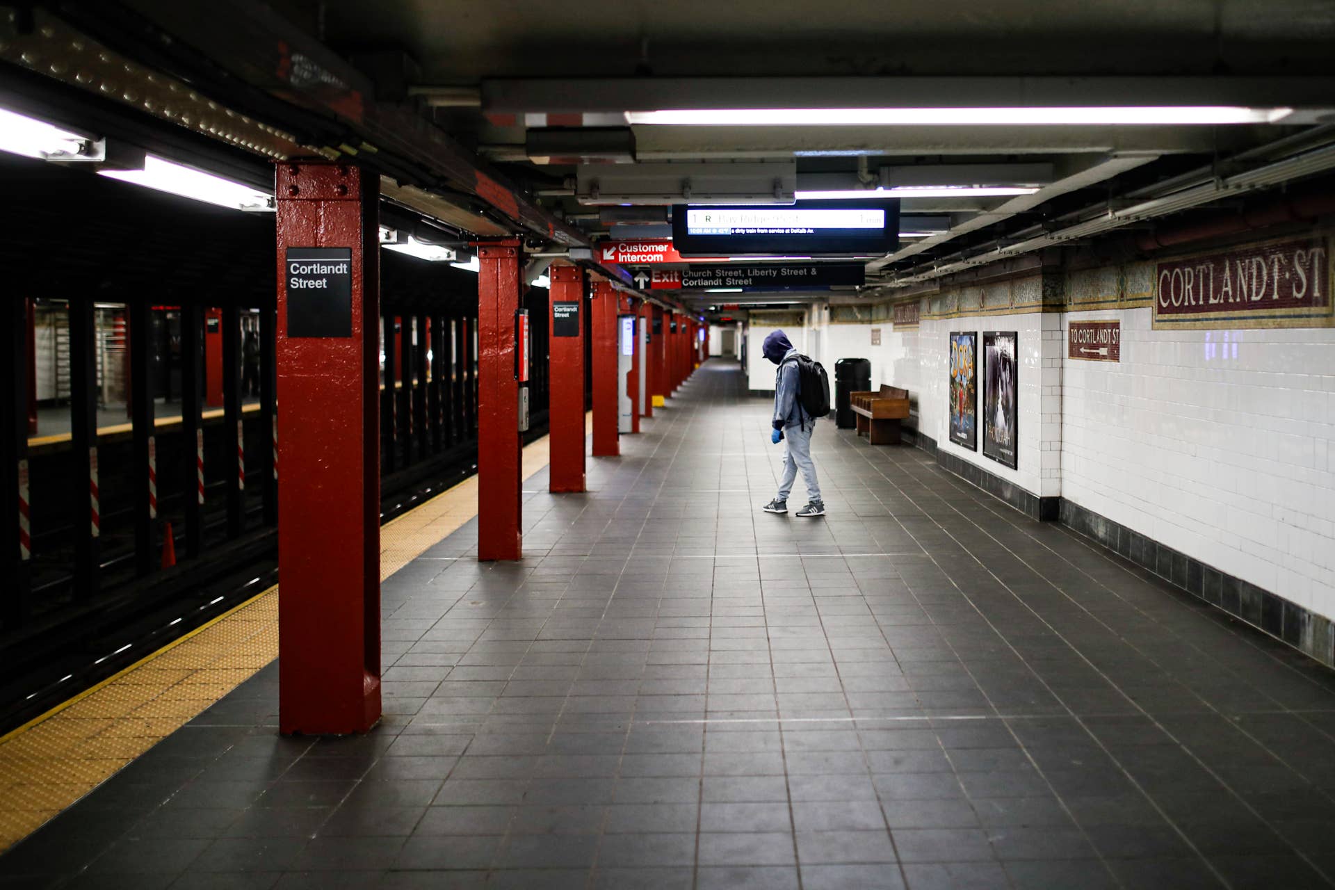A subway customer wears protective gloves and a face mask due to COVID-19 concerns while walking along an empty train platform at the Cortlandt Street station, Saturday, March 21, 2020, in the Brooklyn borough of New York. New York Gov. Andrew Cuomo announced sweeping orders Friday that will severely restrict gatherings of any size for the state's more than 19 million residents and will require workers in nonessential businesses to stay home. (AP Photo/John Minchillo)
