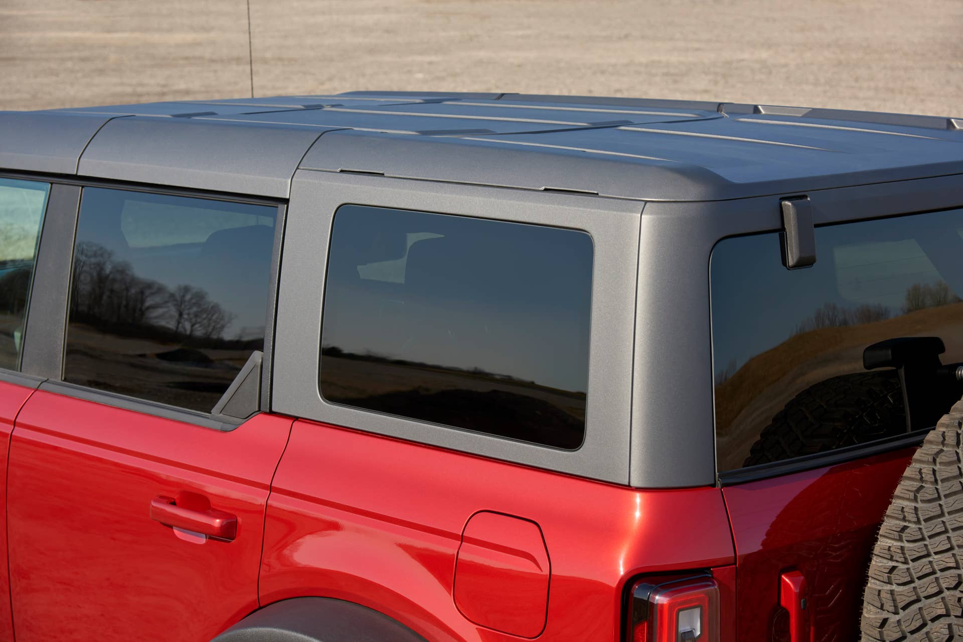 Close up of Bronco four-door First Edition in Rapid Red Metallic Tinted Clearcoat with molded in color (MIC) hardtop. Top features the same four piece design as the four door modular top, however, the rear side glass windows cannot be removed.