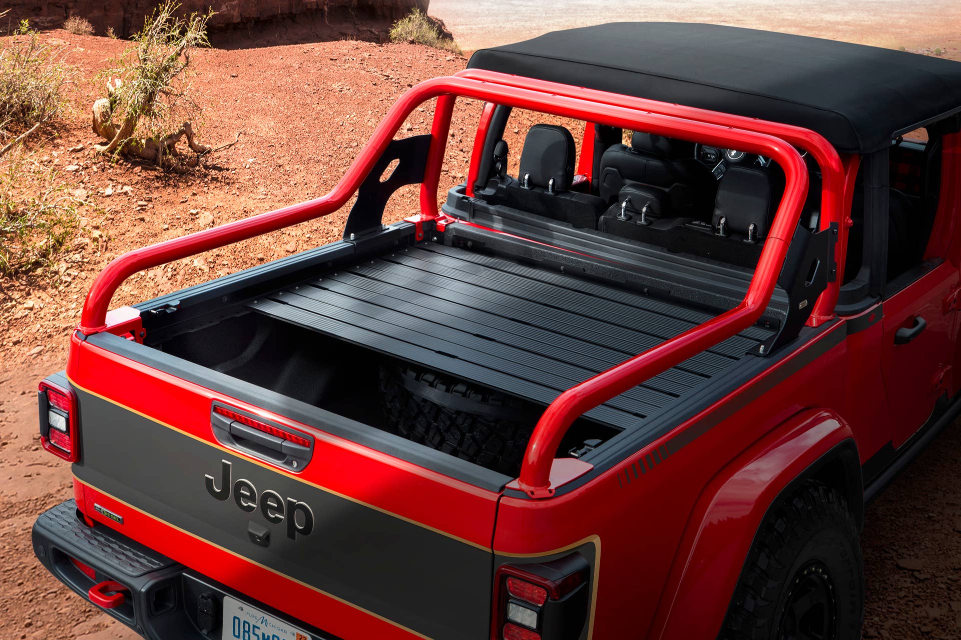 Gladiator Red Bare boasts a Fire Cracker Red exterior with custom Matte Black graphics and gold accents, a black factory soft top and half doors for open-air freedom, plus a cargo bed-mounted sport bar and bed cover and rack system to store tons of off-roading gear.