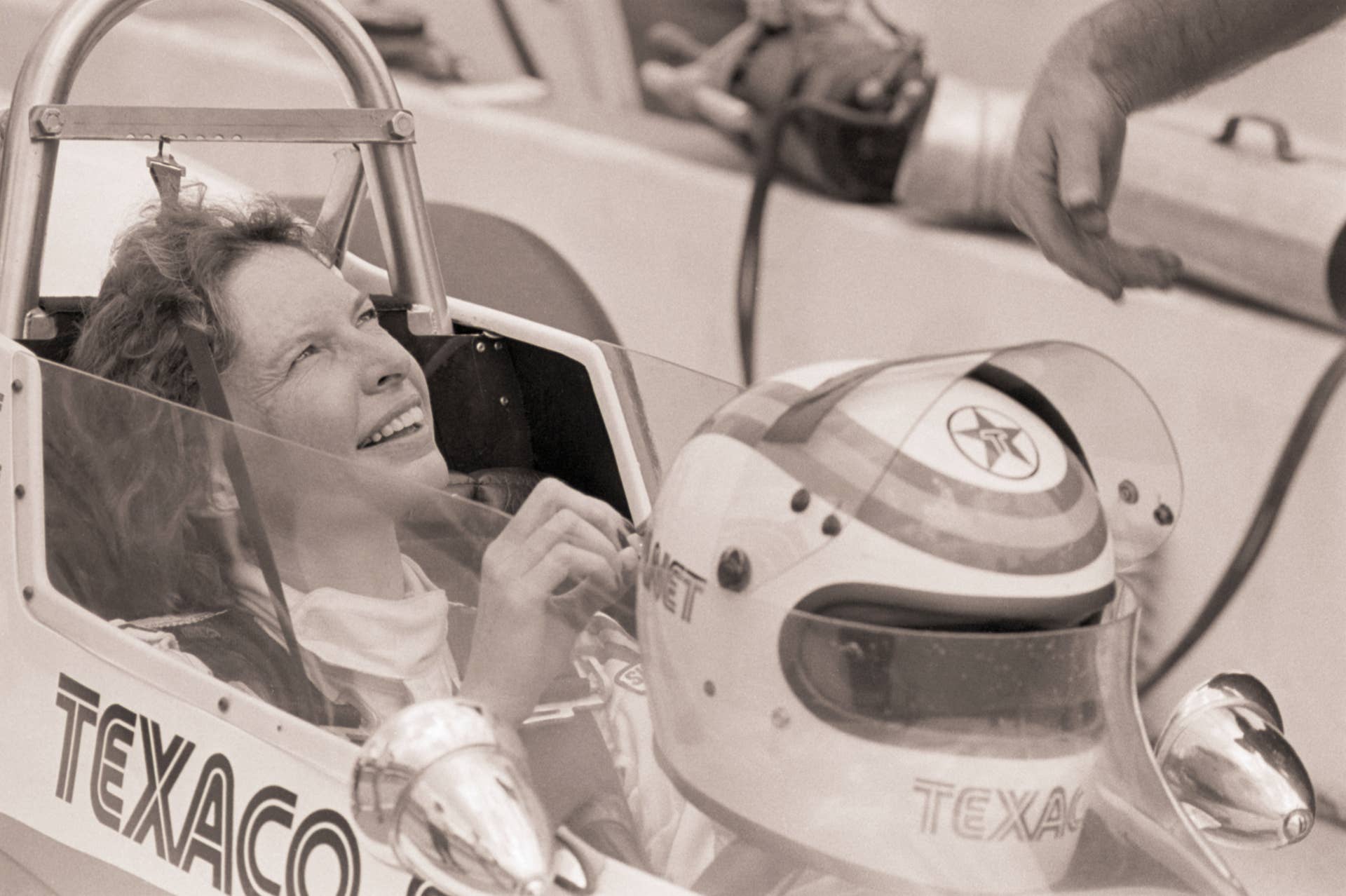 (Original Caption) 5/11/1979-Indianapolis, IN- Janet Guthrie gives a smile to her pit crew after turning in a few practice laps at a speed of 180 MPH. Qualifications begin at 11 AM for the 63rd annual running of the Indianapolis 500 Classic.