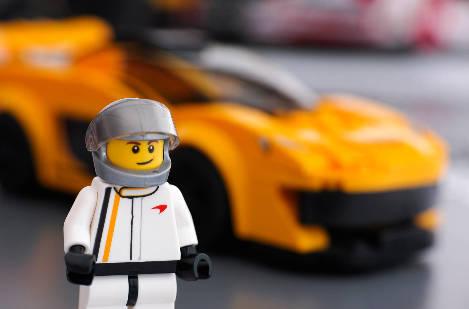 Tambov, Russian Federation - March 09, 2015: Lego McLaren P1 driver minifigure by LEGO Speed Champions and his car on background. Focus on the driver uniform. Studio shot.