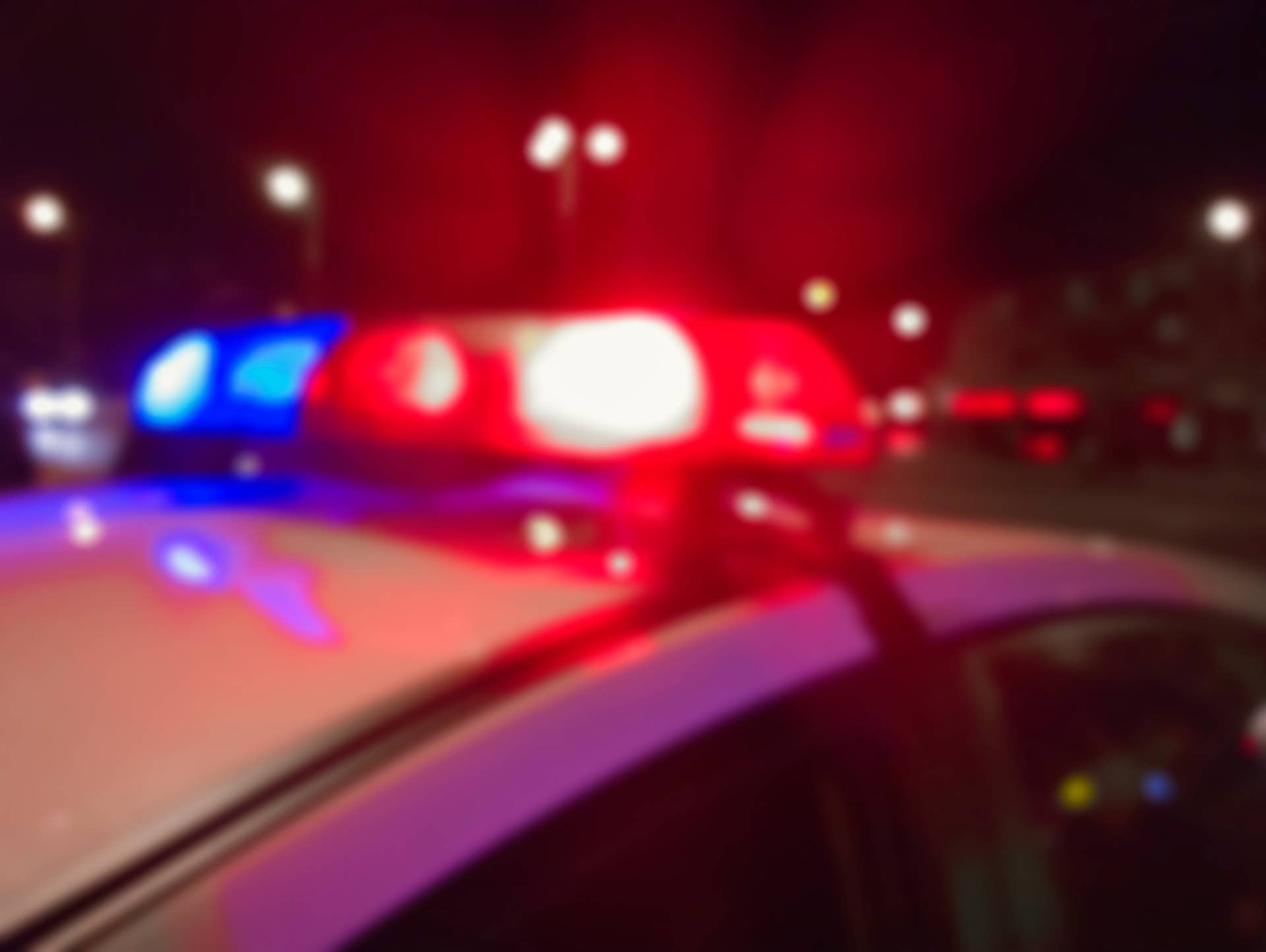 Red and blue lights of police car in night time, crime scene. Night patrolling the city. Abstract blurry image.