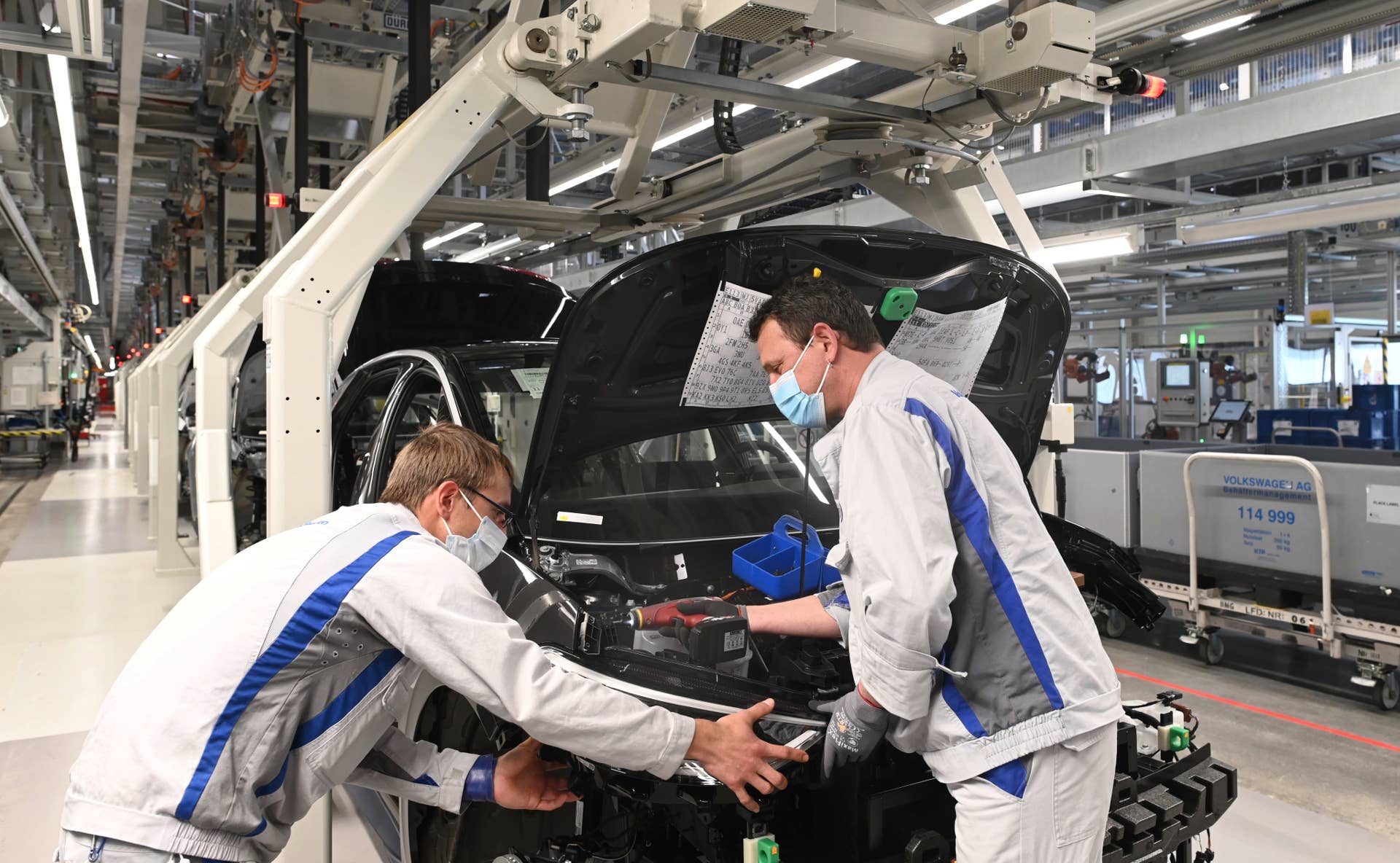 Two employees at Volkswagen in Zwickau install the headlight on the ID.3. For the restart of production, a catalogue of measures for health protection was agreed between the company and the works council, which provides for the wearing of mouth-nose protection at workplaces with a distance of less than 1. 5 metres from each other.