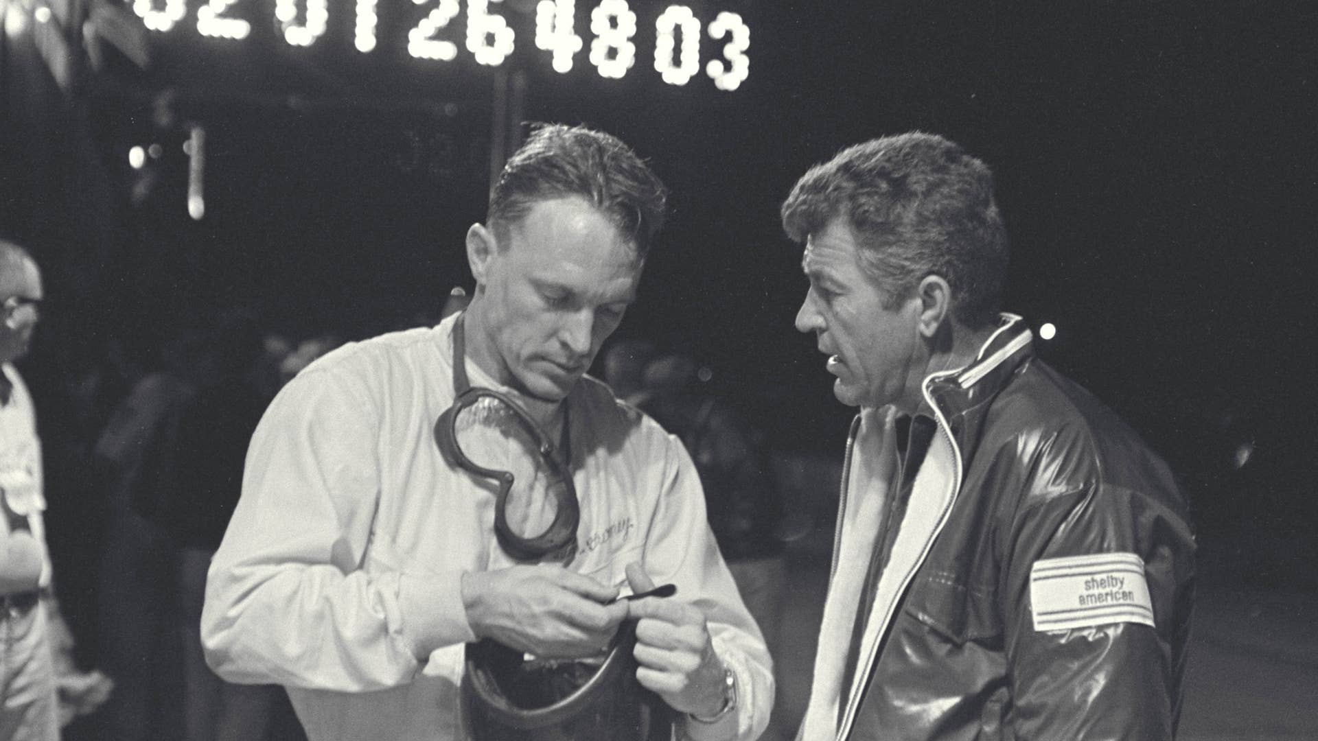 Sebring 12 Hour Race, Sebring, FL, 1966. Dan Gurney (left) and Carroll Shelby (right) talk during a night pit stop of the Sebring 12 Hour Race.