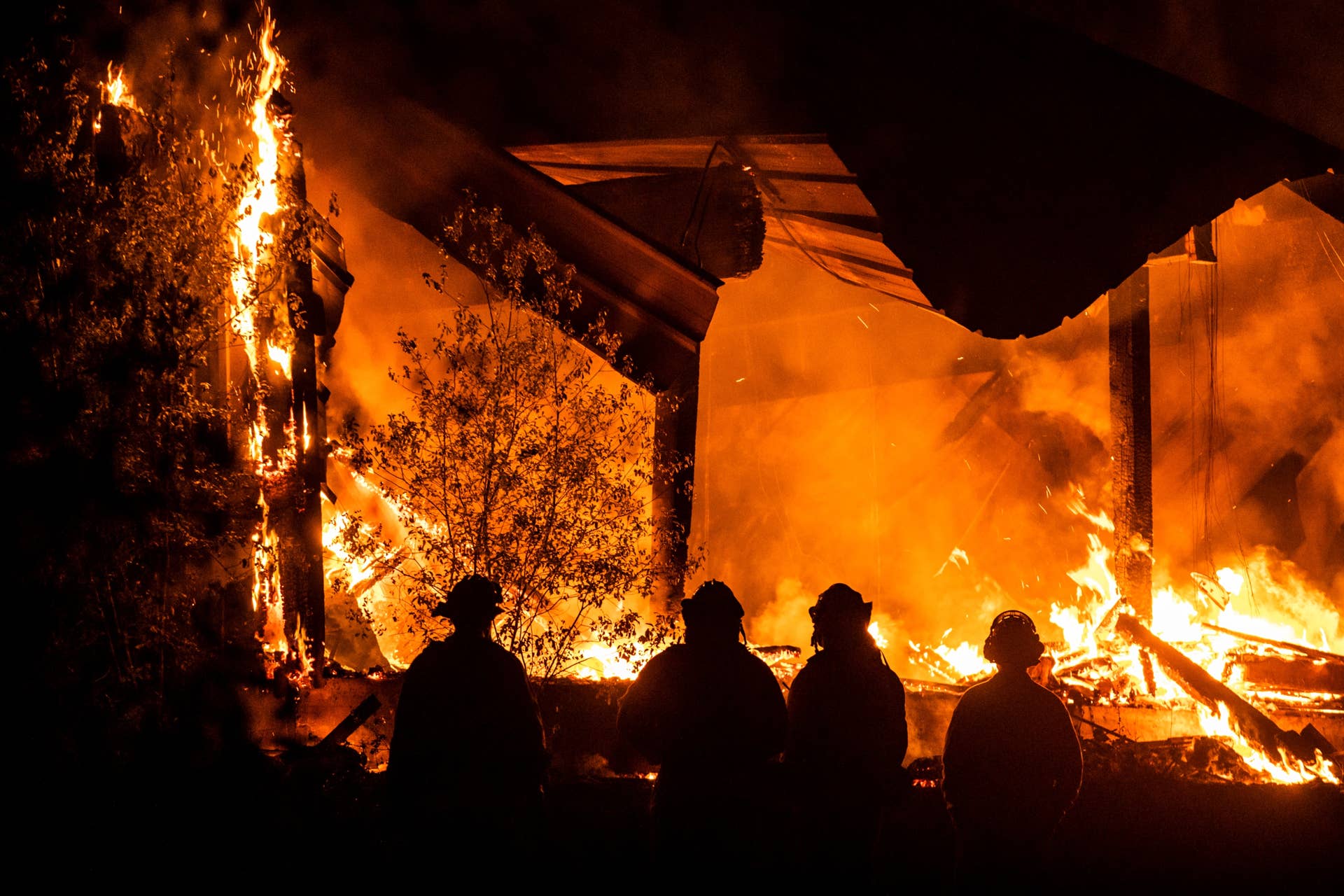 Firefighters look on as a structure burns during the Kincade fire off Highway 128, east of Healdsburg, California on October 29, 2019. - California braced on October 29 for the most powerful winds this season that threaten to spread destructive fires raging in the state and could spark new blazes. (Photo by Philip Pacheco / AFP) (Photo by PHILIP PACHECO/AFP via Getty Images)