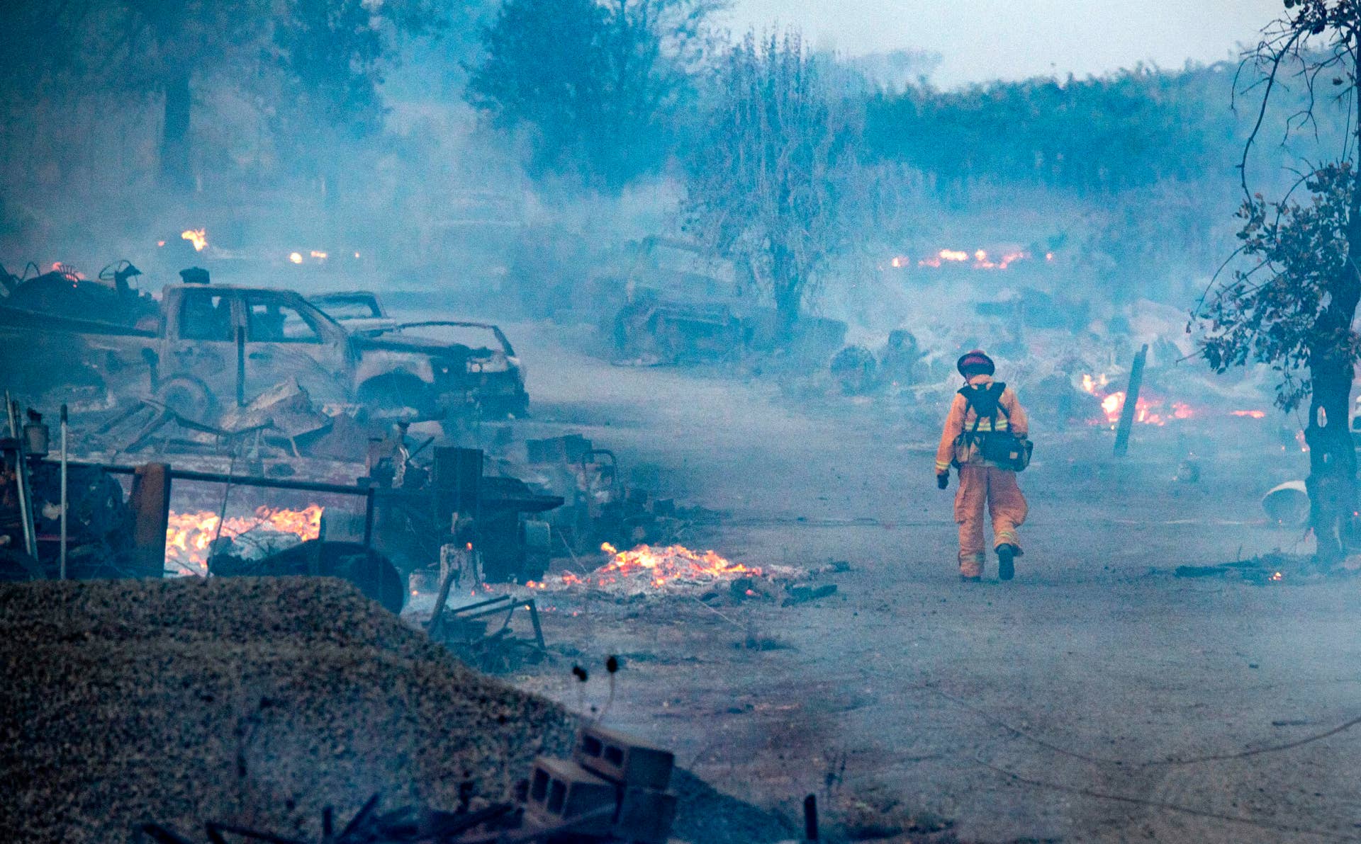 A firefighter walks through a burned property after the Kincade fire tore through Healdsburg, California on October 27, 2019. - Powerful winds were fanning wildfires in northern California in "potentially historic fire" conditions, authorities said October 27, as tens of thousands of people were ordered to evacuate and sweeping power cuts began in the US state. (Photo by Josh Edelson / AFP) (Photo by JOSH EDELSON/AFP via Getty Images)