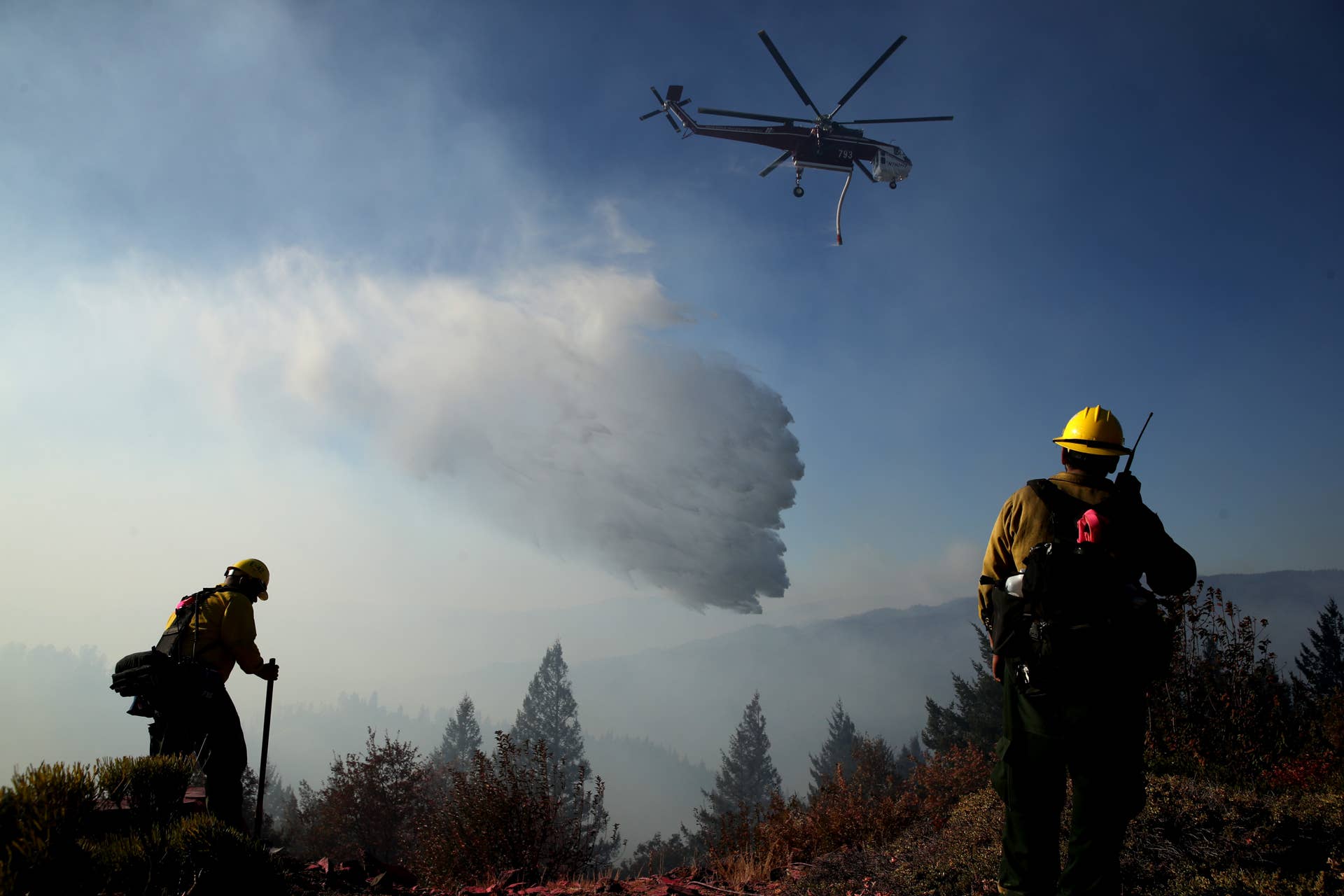 HEALDSBURG, CALIFORNIA - OCTOBER 29: Firefighters stand in the yard of a home as they monitor air operations battling the Kincade Fire on October 29, 2019 in Healdsburg, California. Fueled by high winds, the Kincade Fire has burned over 76,000 acres and has prompted nearly 200,000 evacuations in Sonoma County and beyond.  96 structures have been destroyed and nearly 80,000 homes are still threatened. The fire is 15 percent contained. (Photo by Justin Sullivan/Getty Images)