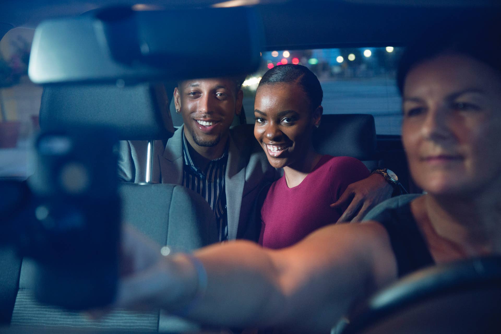 Young couple enjoy a night out using a taxi service booked through an app on their mobile device