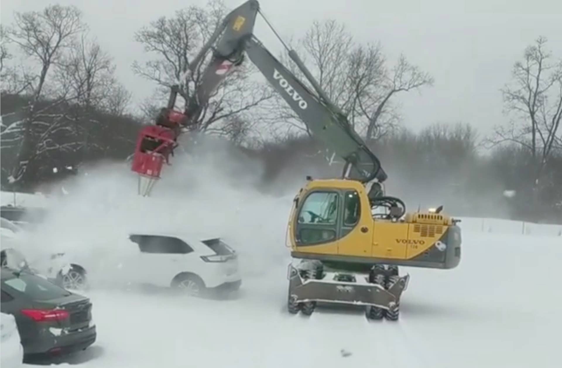 A turbine-equipped excavator clears snow from cars