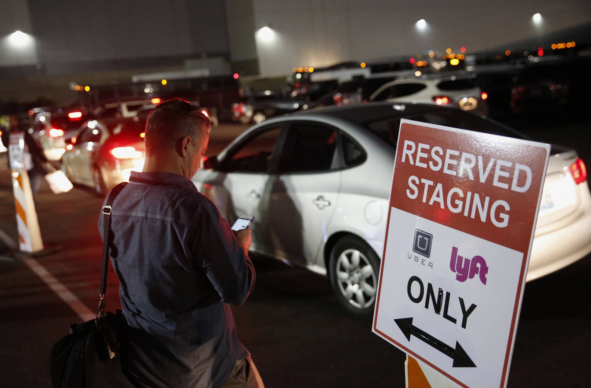 An attendee waits for a ride in the Uber Technologies Inc. and Lyft Inc. reserved staging area during the 2016 Consumer Electronics Show (CES) in Las Vegas, Nevada, U.S., on Wednesday, Jan. 6, 2016. CES is expected to bring a range of announcements from major names in tech showcasing new developments in virtual reality, self-driving cars, drones, wearables, and the Internet of Things. Photographer: Patrick T. Fallon/Bloomberg via Getty Images