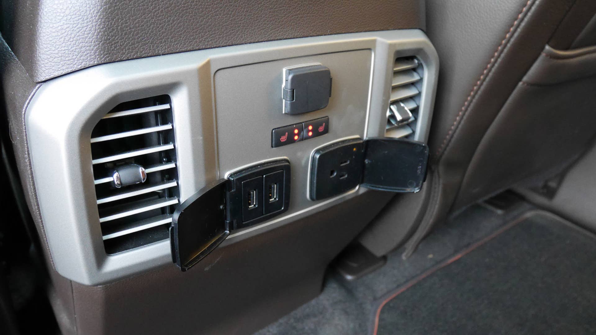 A house-style plug, two USB ports and a cigarette-lighter-style outlet are in the back seat.