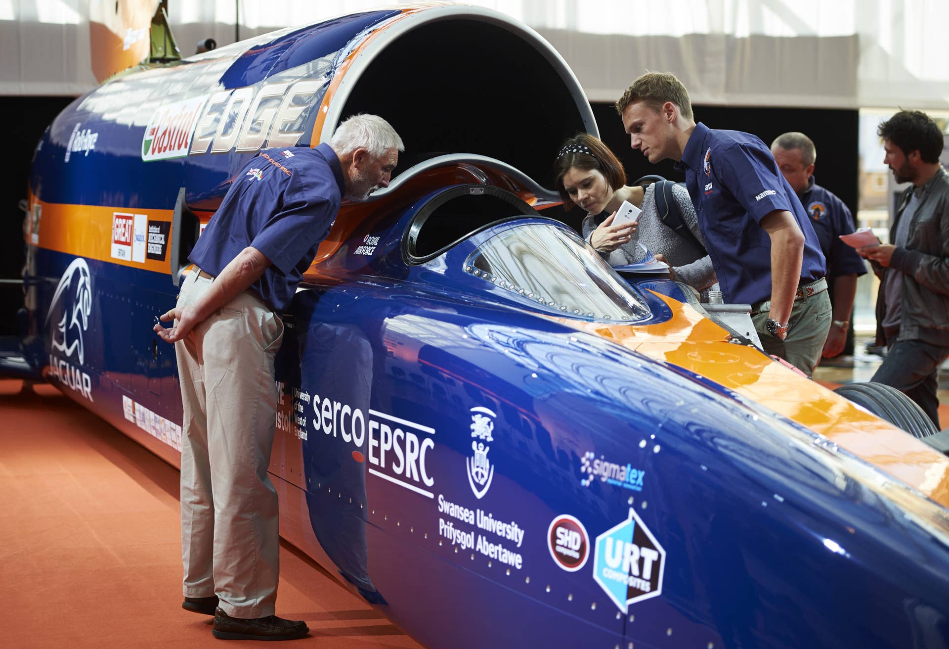 Visitors look at the Bloodhound Supersonic Car as it stands on display during a photocall to promote its World Debut, at Canary Wharf in east London on September 24, 2015. The team behind the Bloodhound SCC is hoping to break the world land speed record in South Africa in 2016. The supersonic car is a mix of car and aircraft technology, and is powered by a jet engine and a rocket together with a petrol engine auxillary power unit. AFP PHOTO / NIKLAS HALLE'N (Photo credit should read NIKLAS HALLE'N/AFP/Getty Images)