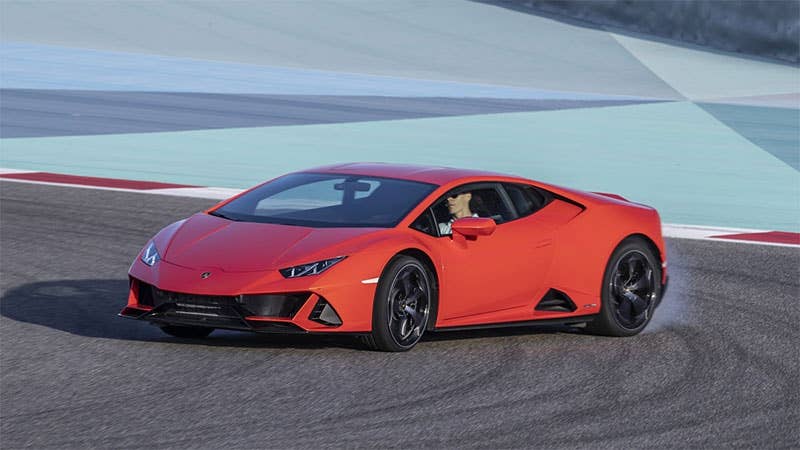 The latest Lamborghini V10 coupe power slides around the track during the press drive. Front three-quarter view.