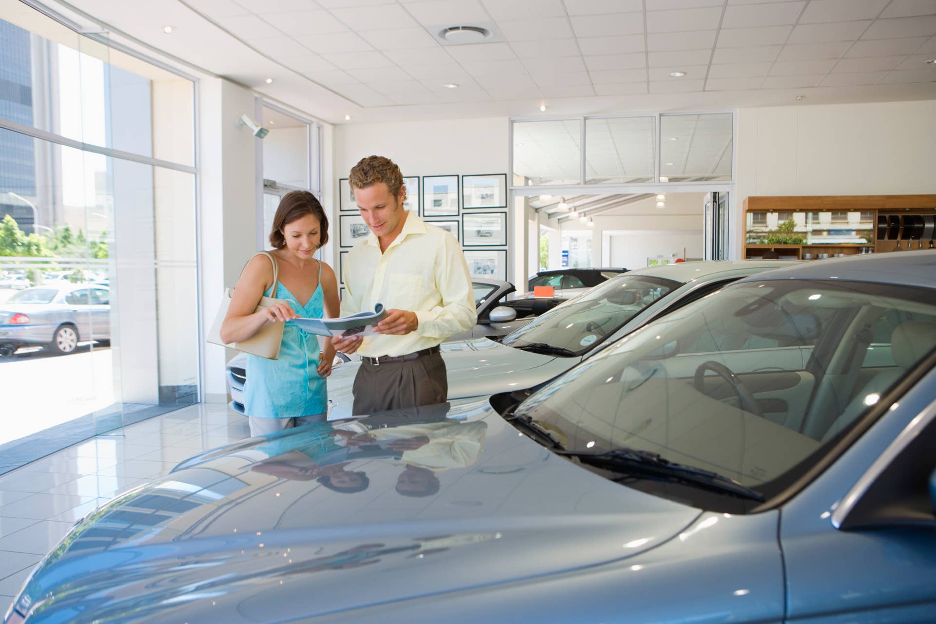 Man and woman looking at brochure in car dealership