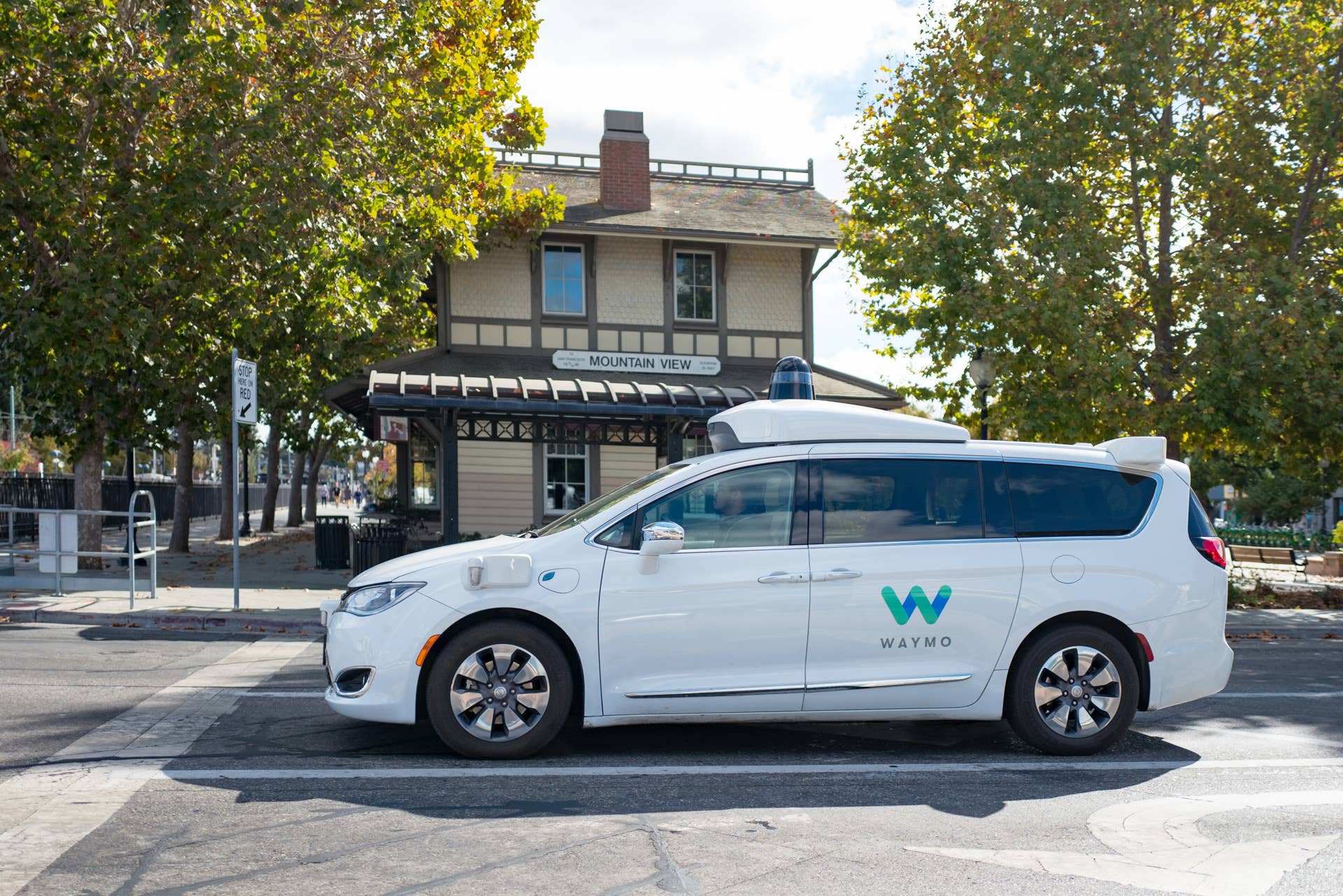 Close-up of self driving minivan, with LIDAR and other sensor units and logo visible, part of Google parent company Alphabet Inc, driving past historic railroad station with sign reading Mountain View, in the Silicon Valley town of Mountain View, California, with safety driver visible, October 28, 2018. (Photo by Smith Collection/Gado/Getty Images)