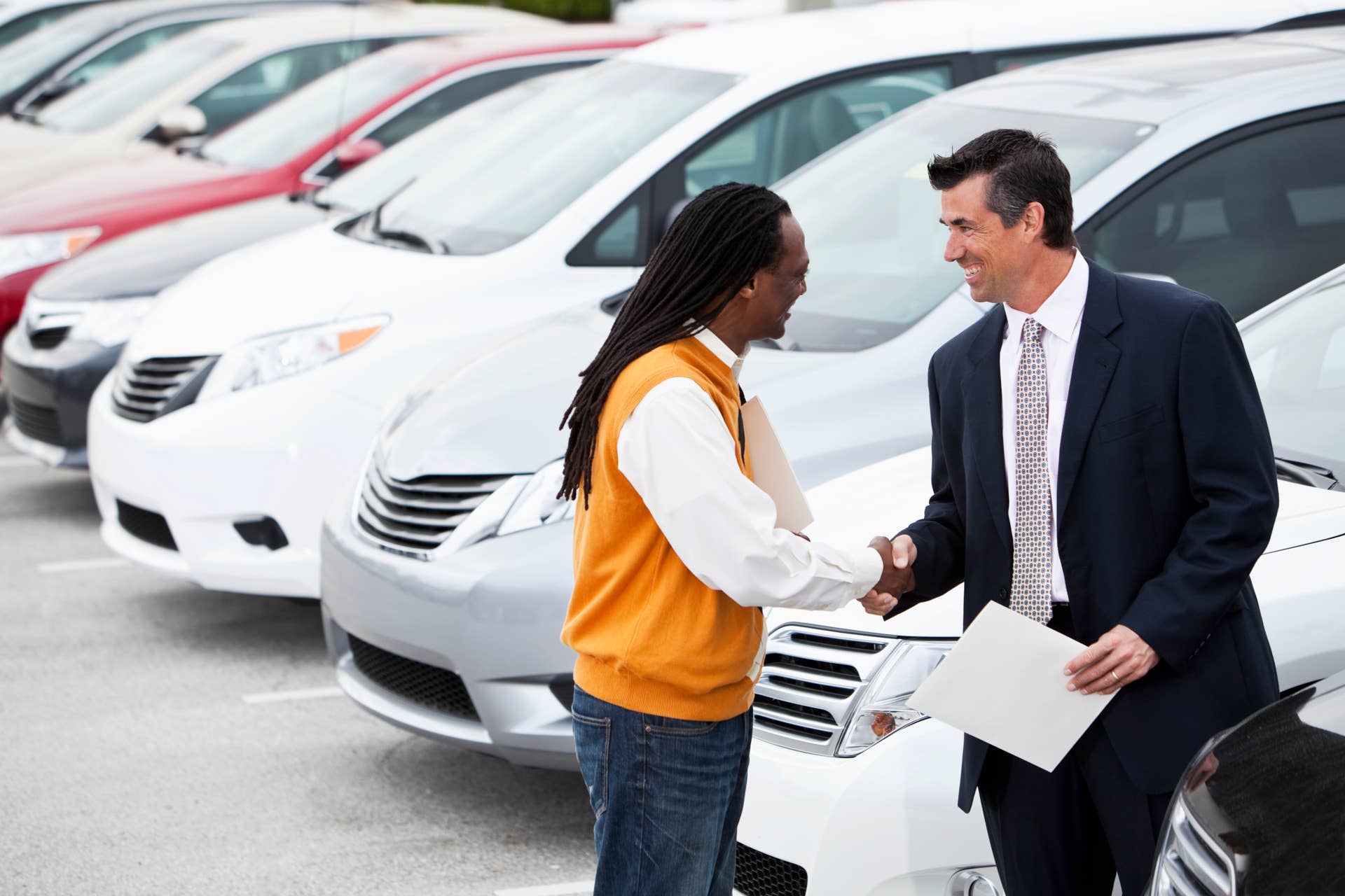 African American man (40s) shaking hands with car salesman. Shallow DOF, focus on foreground.