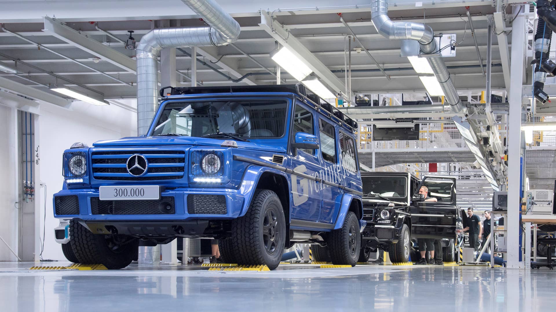 : Im Magna Steyr-Werk (Ãsterreich) ist die 300.000 G-Klasse vom Band gelaufen. Die legendären Gelände-Eigenschaften und der Abenteurer-Charakter werden durch das Offroad-Paket einschlieÃlich schwarzer 16-Zoll Räder mit All-Terrain-Reifen und einem robusten Dachträger weiter verstärkt.;Kraftstoffverbrauch kombiniert: 12,3l/100 km; CO2-Emissionen kombiniert: 289 g/km* The 300,000th G-Class has left the production line at the Magna Steyr plant in Austria. The legendary off-road qualities and adventurer character of the G-Class are enhanced by the Off-Road package including black 16-inch wheels with all-terrain tyres and a robust roof rack.;Fuel consumption combined: 12.3 l/100 km; combined CO2 emissions: 289 g/km*