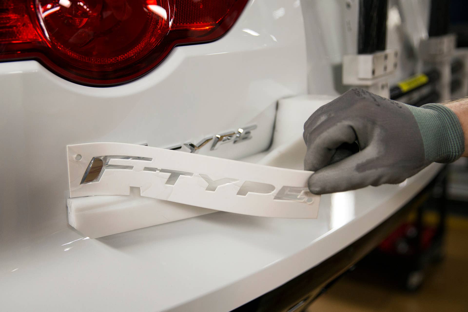 An employee removes a template after fitting an F-type badge to the rear of a luxury Jaguar automobile, produced by Jaguar Land Rover Plc, a unit of Tata Motors Ltd., at the company's assembly plant in Castle Bromwich, U.K., on Monday, June 9, 2014. The International Monetary Fund underestimated the strength of the U.K. economy in its earlier warning against the government's austerity program, Managing Director Christine Lagarde said. Photographer: Simon Dawson/Bloomberg via Getty Images
