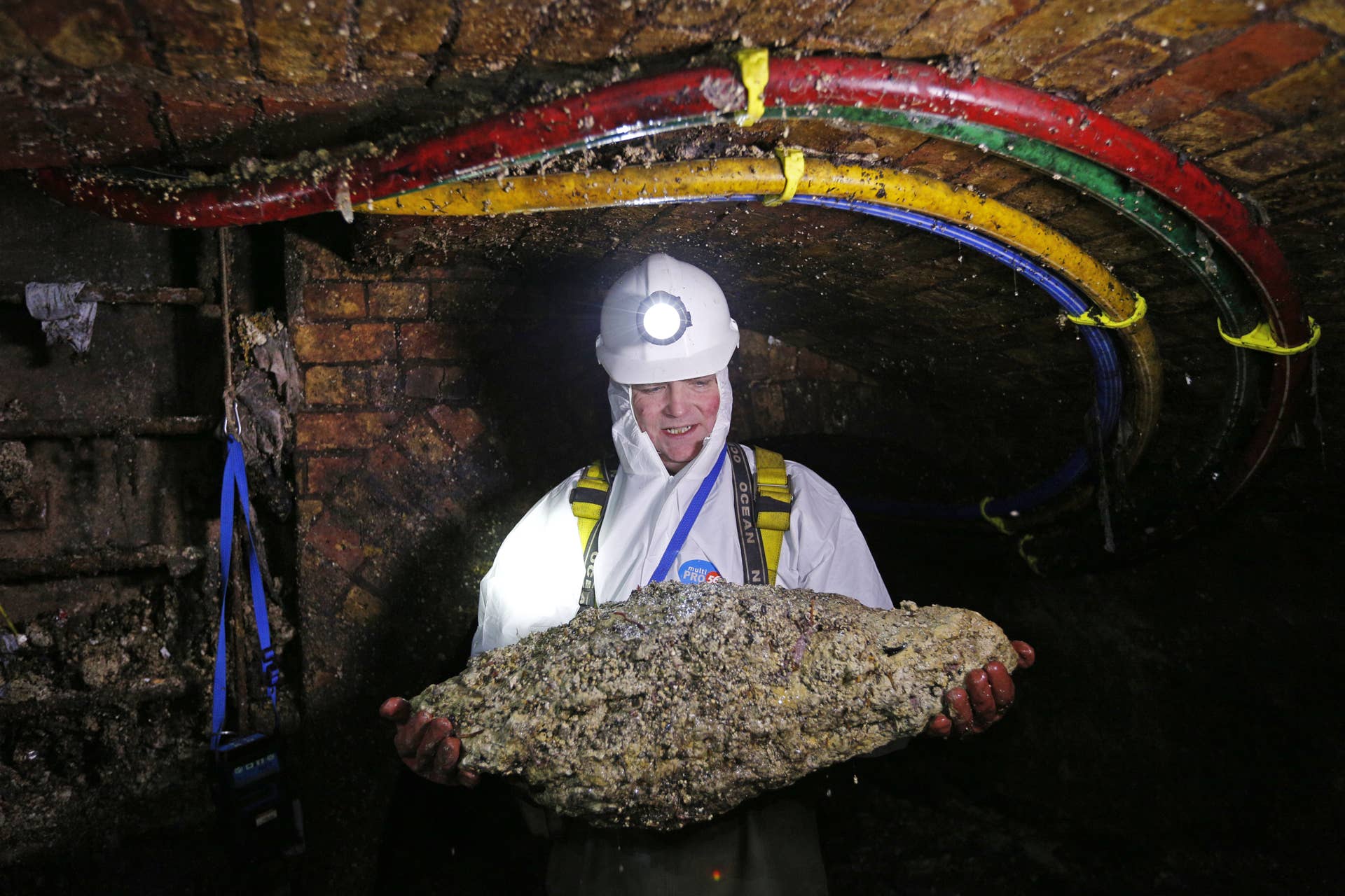 TO GO WITH AFP STORY BY ROBIN MILLARD Tim Henderson, a 'flusher' or trunk sewer technician holds a 'fatberg' as he works in the intersection of the Regent Street and Victoria sewer in London on December 11, 2014. Every day beneath the streets of London, sewer cleaners are fighting a grim war against giant 'fatbergs' clogging the system. Congealed fat is blocking up the Victorian sewers and the problem is to get worse at Christmas. An extra two Olympic-sized swimming pools of turkey fat will be tipped down the drains during the festive season. There are 80,000 fatberg blockages a year, costing Thames Water customers �1 million ($1.6 million, 1.3 million euros) each month to tackle. The company urges people people to dispose of their cooking oil and fat properly. 'Bin it, don't block it' is their message. AFP PHOTO / ADRIAN DENNIS (Photo credit should read ADRIAN DENNIS/AFP/Getty Images)