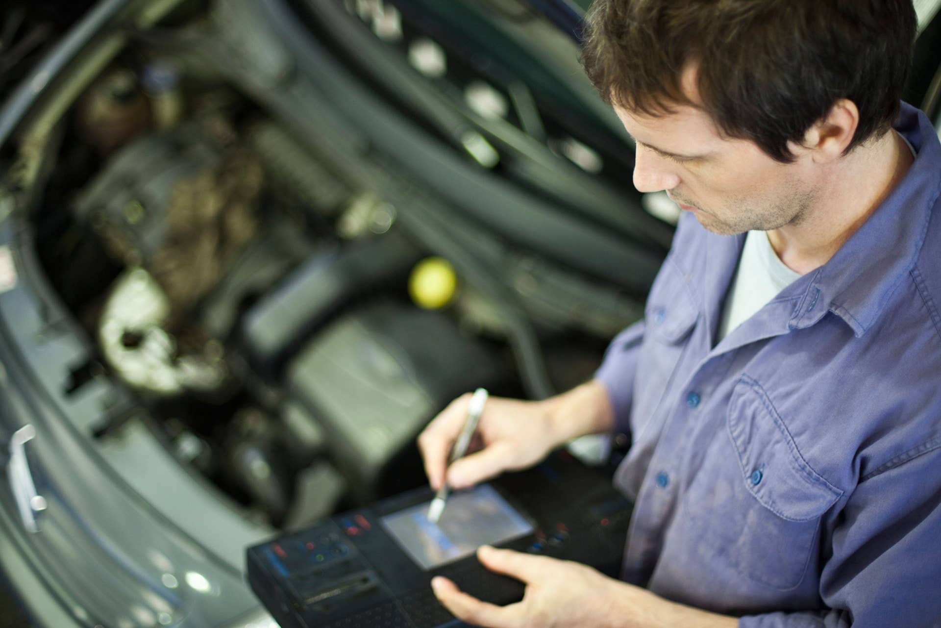 BM8XYM Mechanic using electronic tools to evaluate car performance