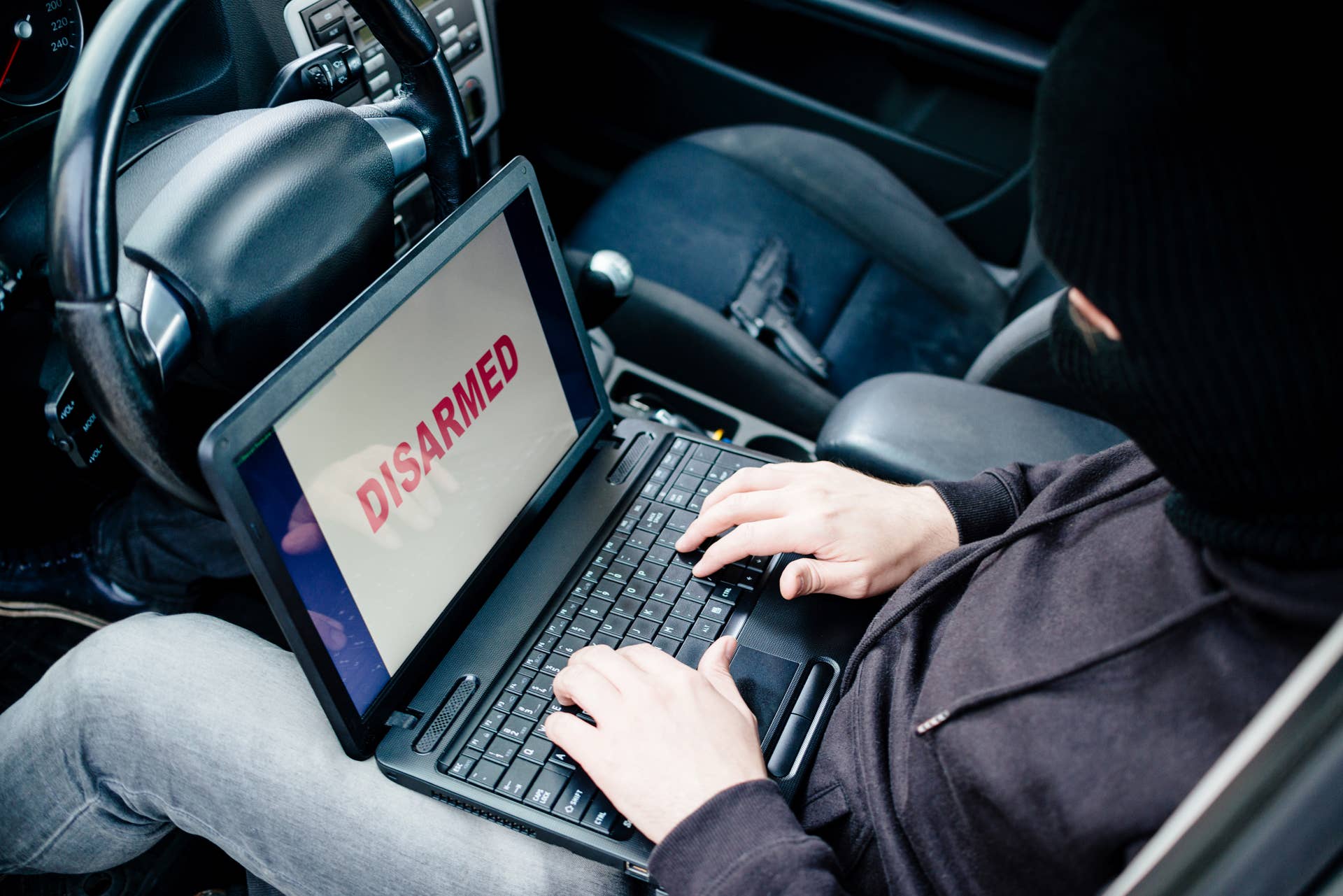 Car thief trying to break car security systems with laptop computer. Car thief, car theft