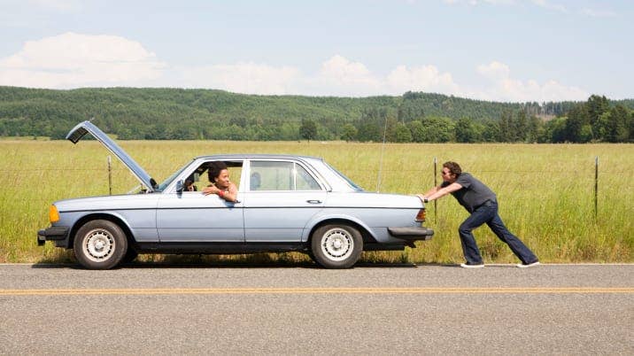 Man pushing broken down car