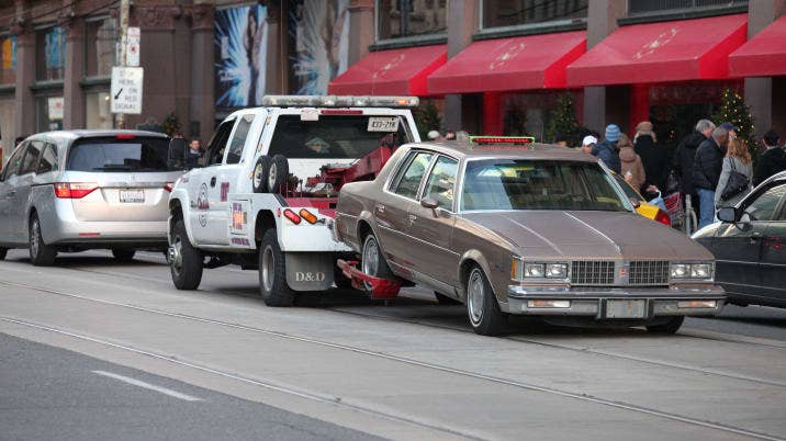 Tow truck hauling a car on street in downtown Toronto Canada