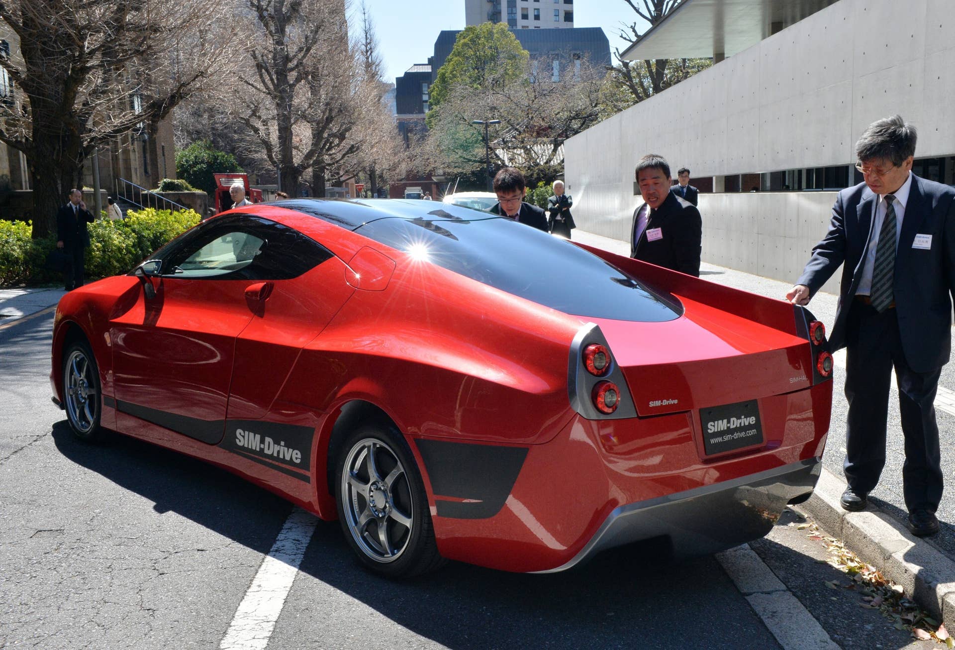 Employees of Japan's electric vehicle venture SIM-Drive dust the fourth generation model of the company's electric vehicle 'SIM-HAL' at the University of Tokyo on March 31, 2014. SIM-HAL has newly developed highly efficient in-wheel motors for all wheels and enables a drive of 400km with a charge.   AFP PHOTO / Yoshikazu TSUNO        (Photo credit should read YOSHIKAZU TSUNO/AFP/Getty Images)