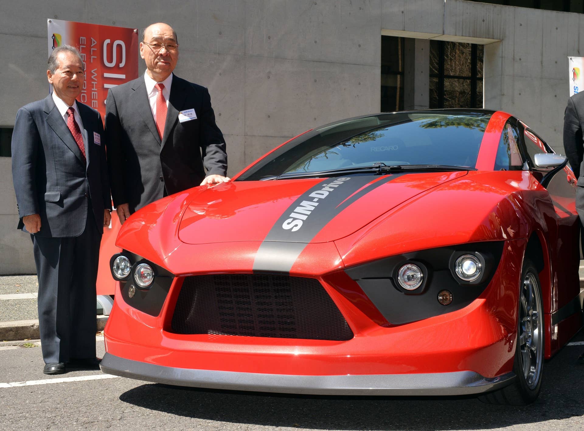 Japan's electric vehicle venture SIM-Drive chairman Soichiro Fukutake (L) and president Nobuhiro Tajima display the fourth generation model of the company's electric vehicle 'SIM-HAL' at the University of Tokyo on March 31, 2014. SIM-HAL has newly developed highly efficient in-wheel motors for all wheels and enables a drive of 400km with a charge.   AFP PHOTO / Yoshikazu TSUNO        (Photo credit should read YOSHIKAZU TSUNO/AFP/Getty Images)