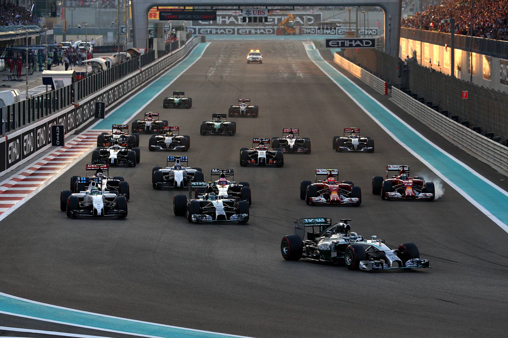 ABU DHABI, UNITED ARAB EMIRATES - NOVEMBER 23:  Lewis Hamilton of Great Britain and Mercedes GP leads Nico Rosberg of Germany and Mercedes GP and the rest if the field into the first turn during the Abu Dhabi Formula One Grand Prix at Yas Marina Circuit on November 23, 2014 in Abu Dhabi, United Arab Emirates.  (Photo by Mark Thompson/Getty Images)