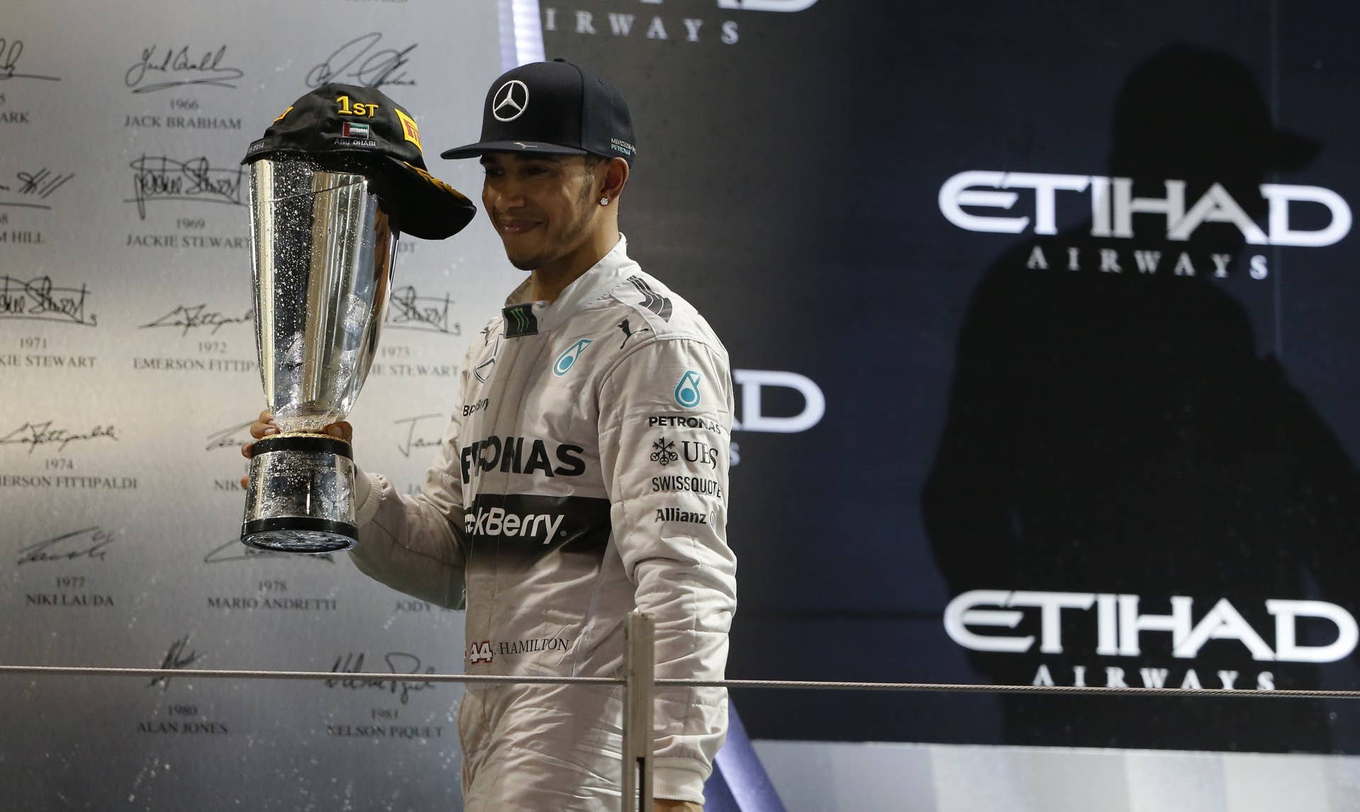 Mercedes-AMG's British driver  Lewis Hamilton  celebrates on the podium at the Yas Marina circuit in Abu Dhabi on November 23, 2014 after the Abu Dhabi Formula One Grand Prix.     AFP PHOTO / KARIM SAHIB        (Photo credit should read KARIM SAHIB/AFP/Getty Images)
