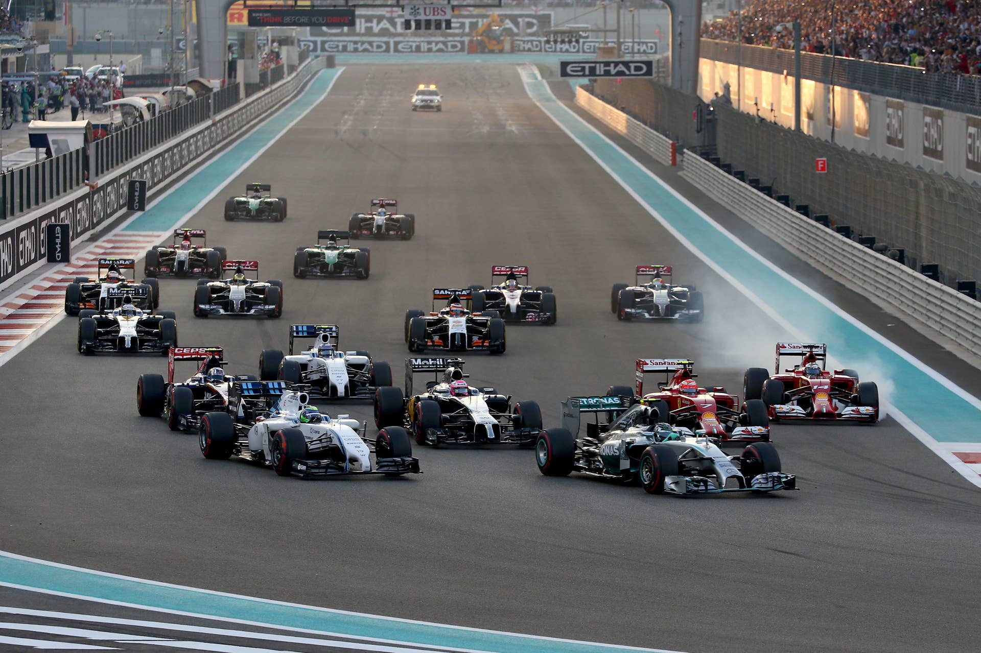 ABU DHABI, UNITED ARAB EMIRATES - NOVEMBER 23:  Lewis Hamilton of Great Britain and Mercedes GP leads Nico Rosberg of Germany and Mercedes GP and the rest if the field into the first turn during the Abu Dhabi Formula One Grand Prix at Yas Marina Circuit on November 23, 2014 in Abu Dhabi, United Arab Emirates.  (Photo by Mark Thompson/Getty Images)