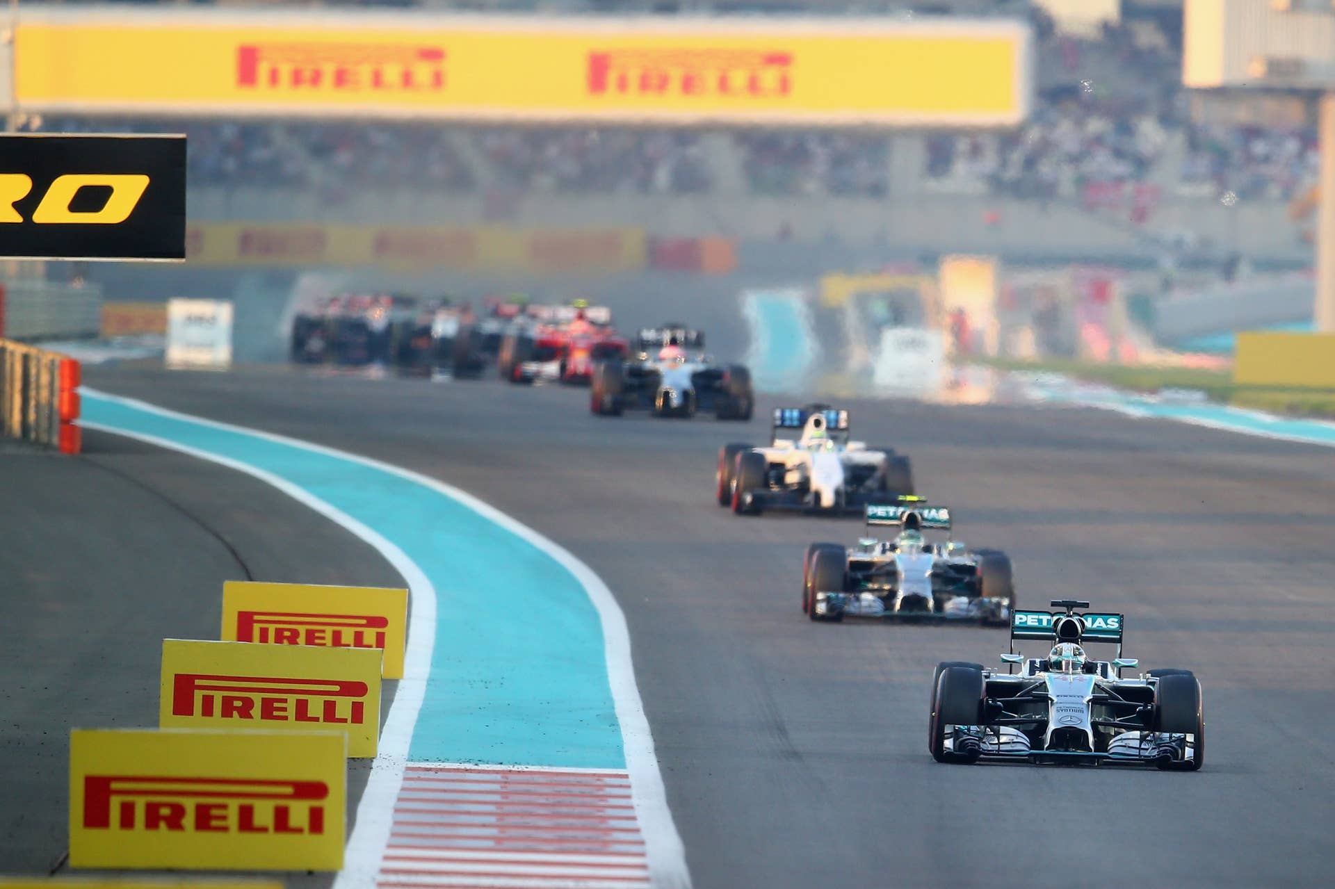 ABU DHABI, UNITED ARAB EMIRATES - NOVEMBER 23:  Lewis Hamilton of Great Britain and Mercedes GP leads Nico Rosberg of Germany and Mercedes GP and the rest of the field during the Abu Dhabi Formula One Grand Prix at Yas Marina Circuit on November 23, 2014 in Abu Dhabi, United Arab Emirates.  (Photo by Clive Rose/Getty Images)